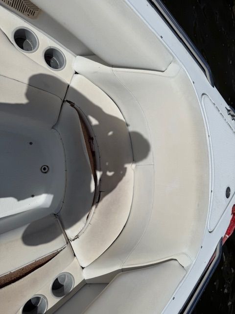 The image shows the bow area of a boat with white upholstery and cup holders.