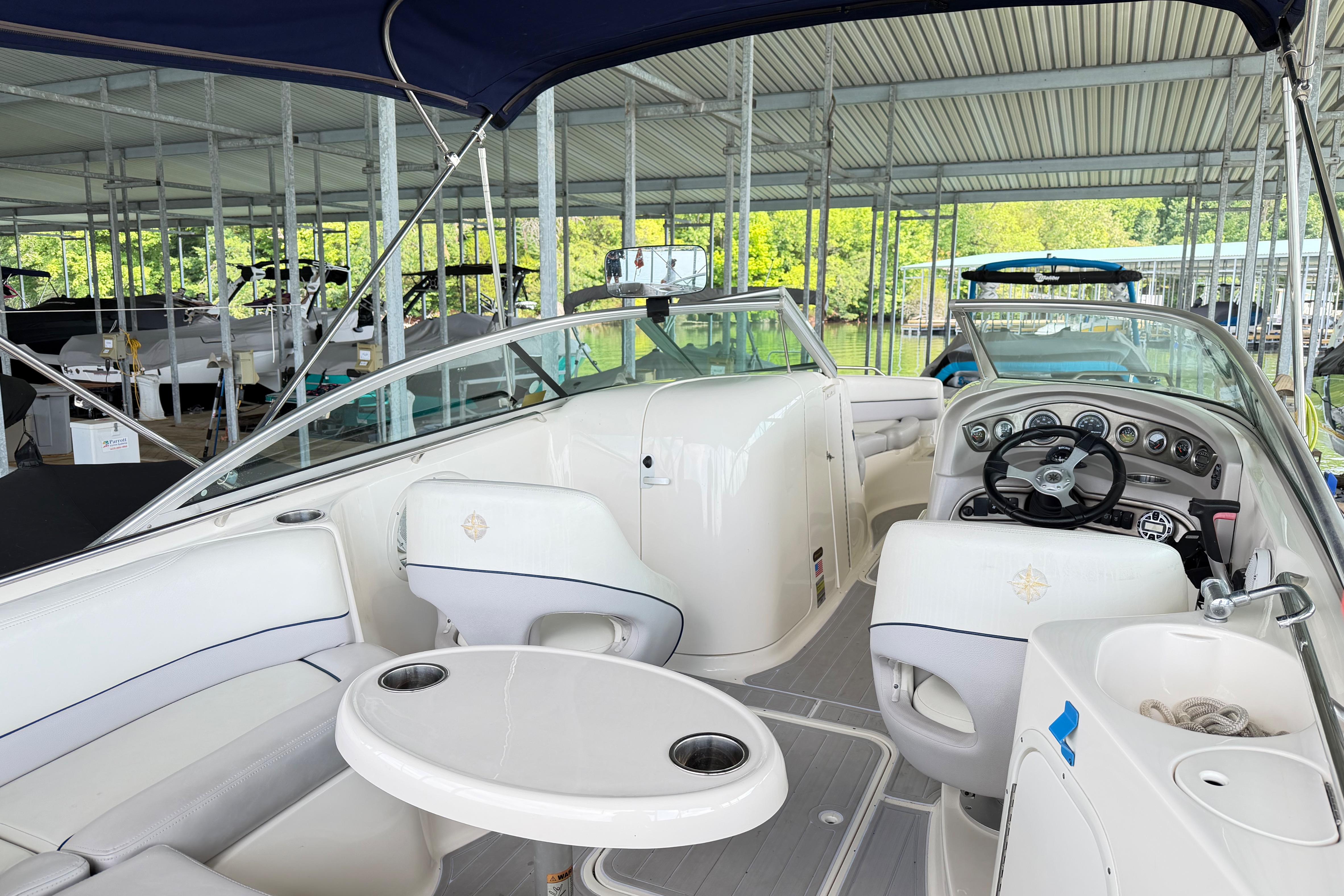 Interior of a 2010 Bryant 255 boat docked, featuring seating and steering wheel.