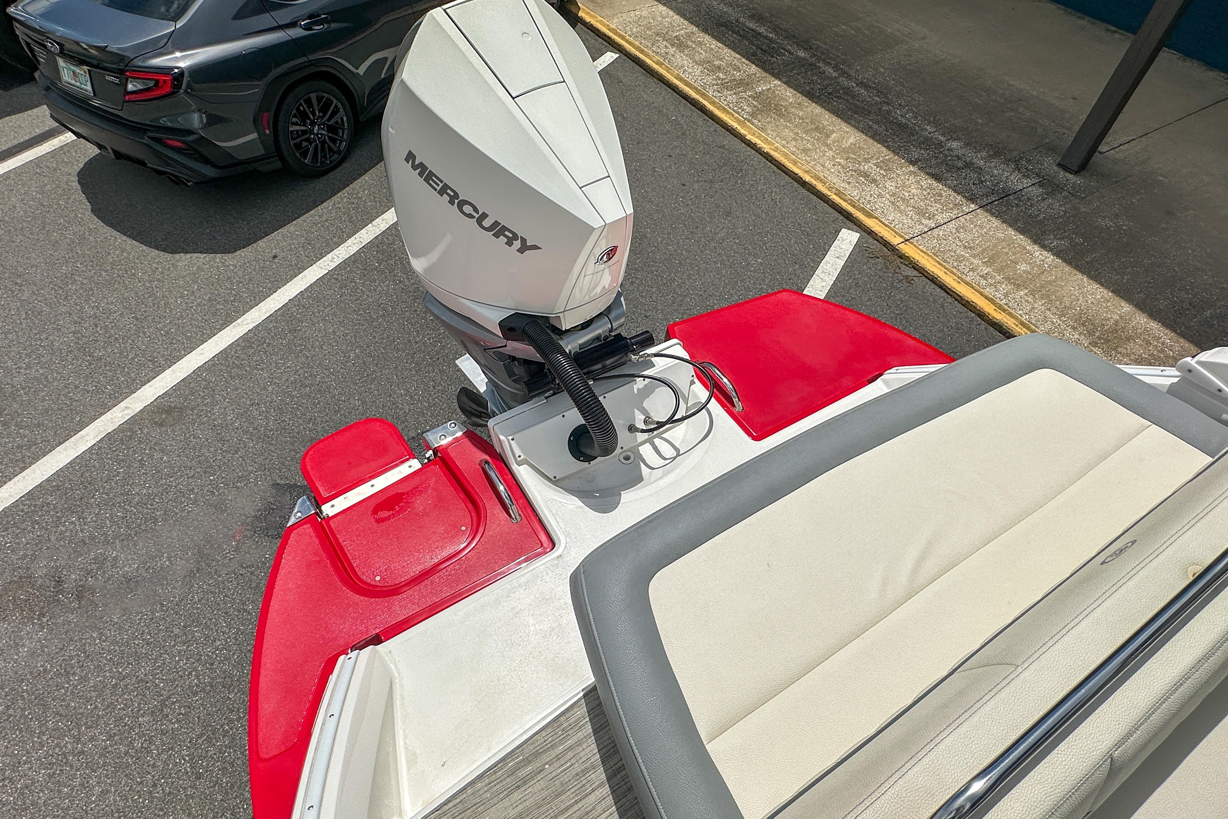 2022 Cobalt 25SC boat with Mercury engine, red and white design, parked near a car.