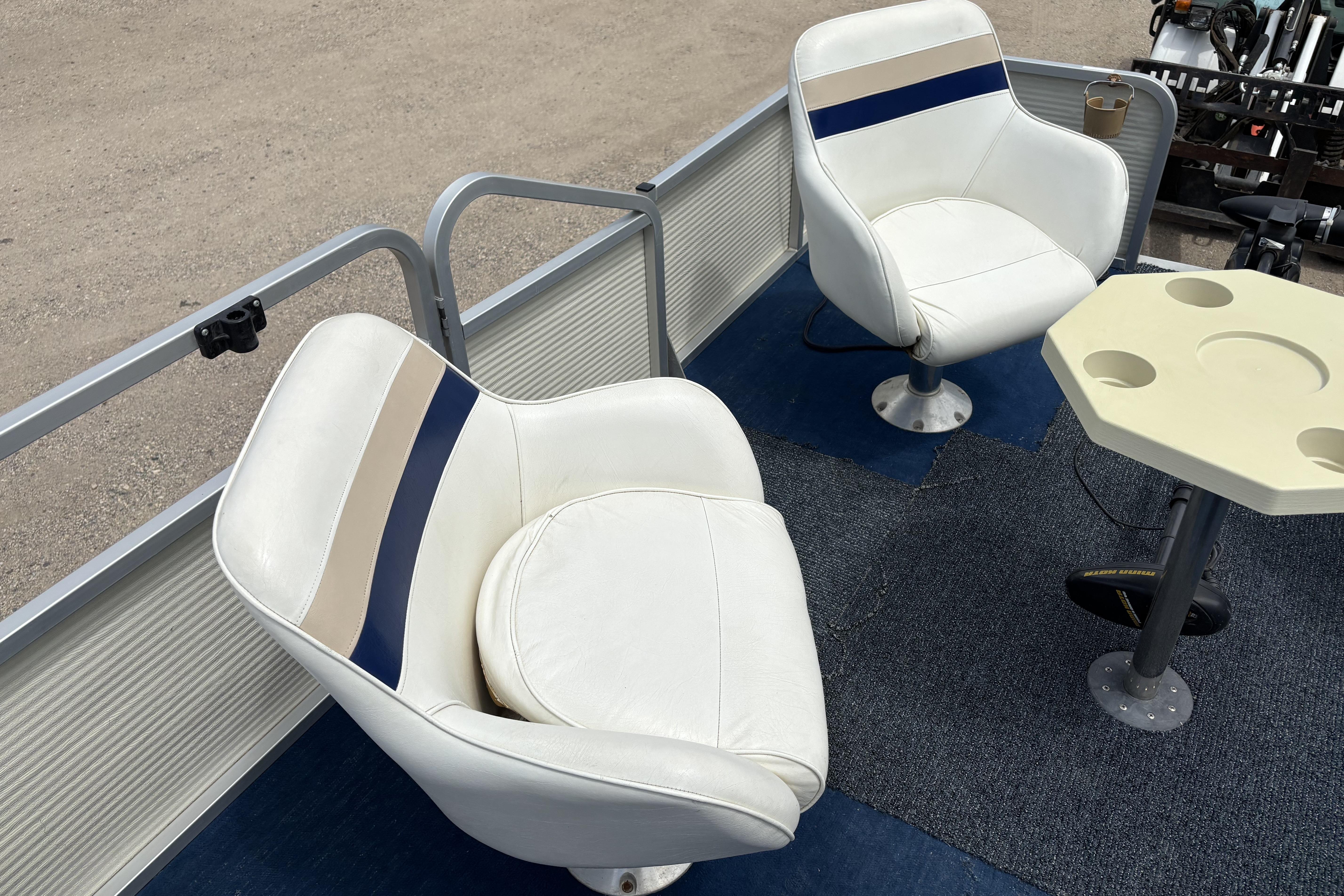 1997 Northwood 24' Pontoon boat interior with white seats and a small table.