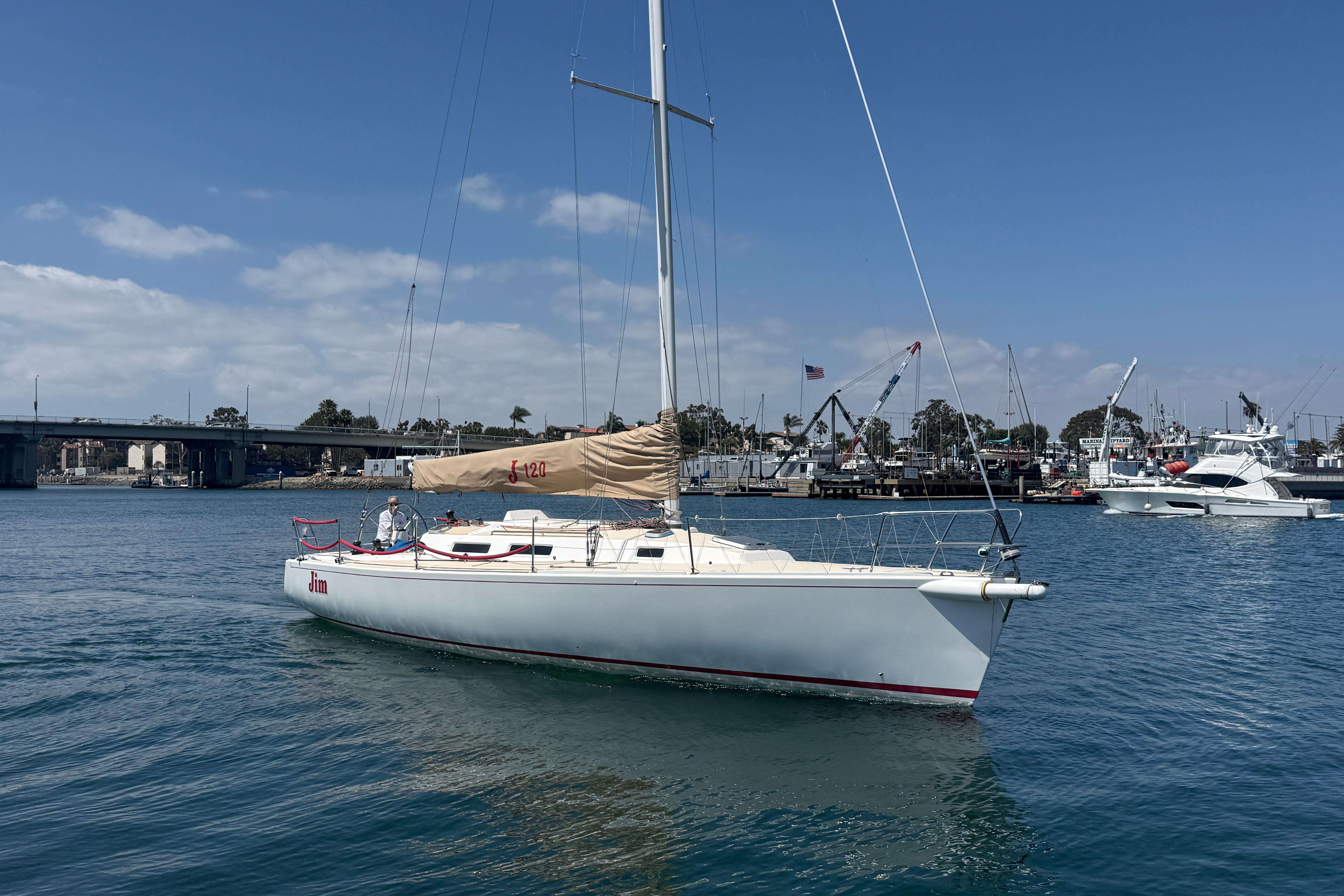 Sailing yacht J/120 from 1999 by J Boats on calm waters near a marina.