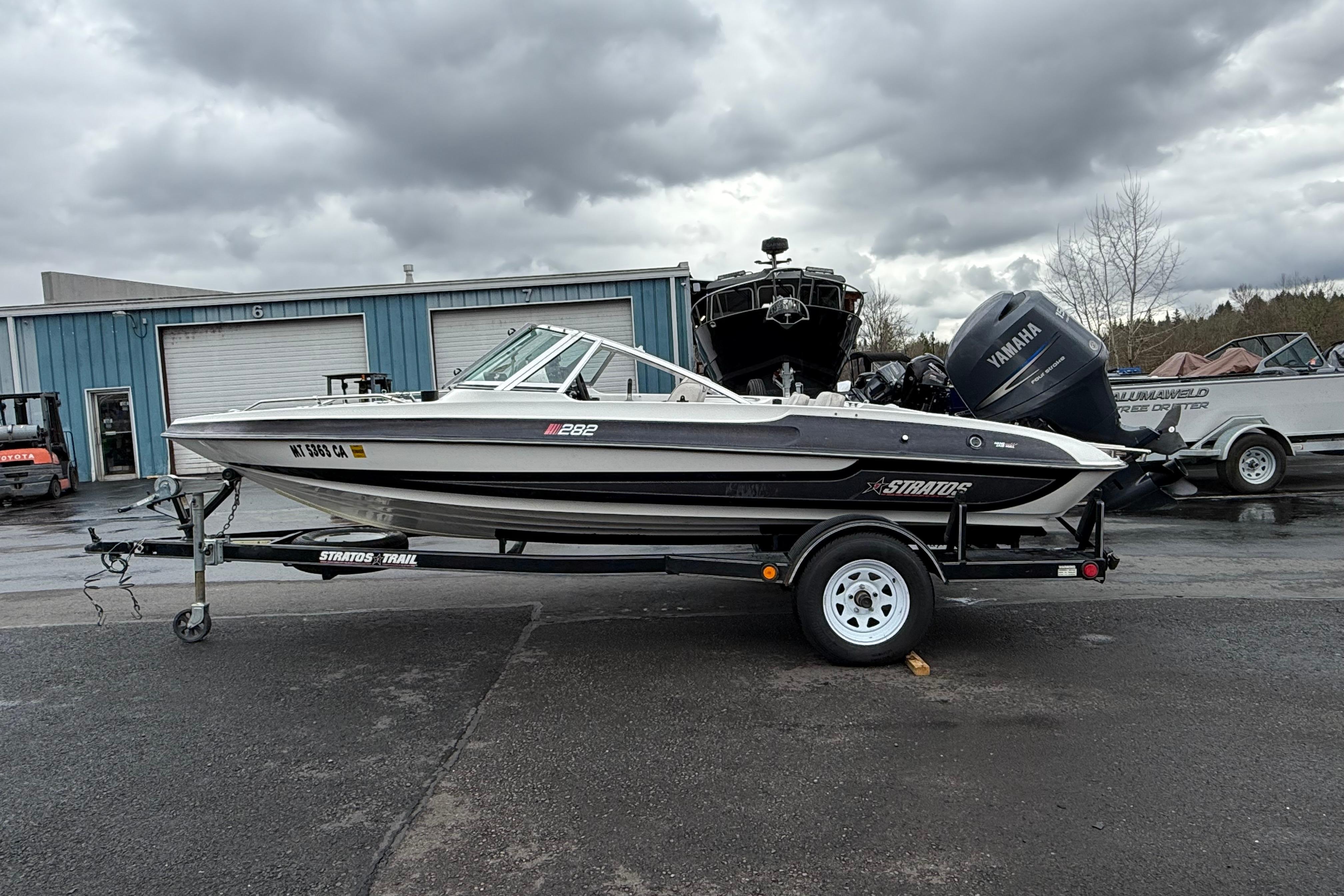 1996 Stratos 283 FS boat on trailer with Yamaha outboard motor, parked outdoors.