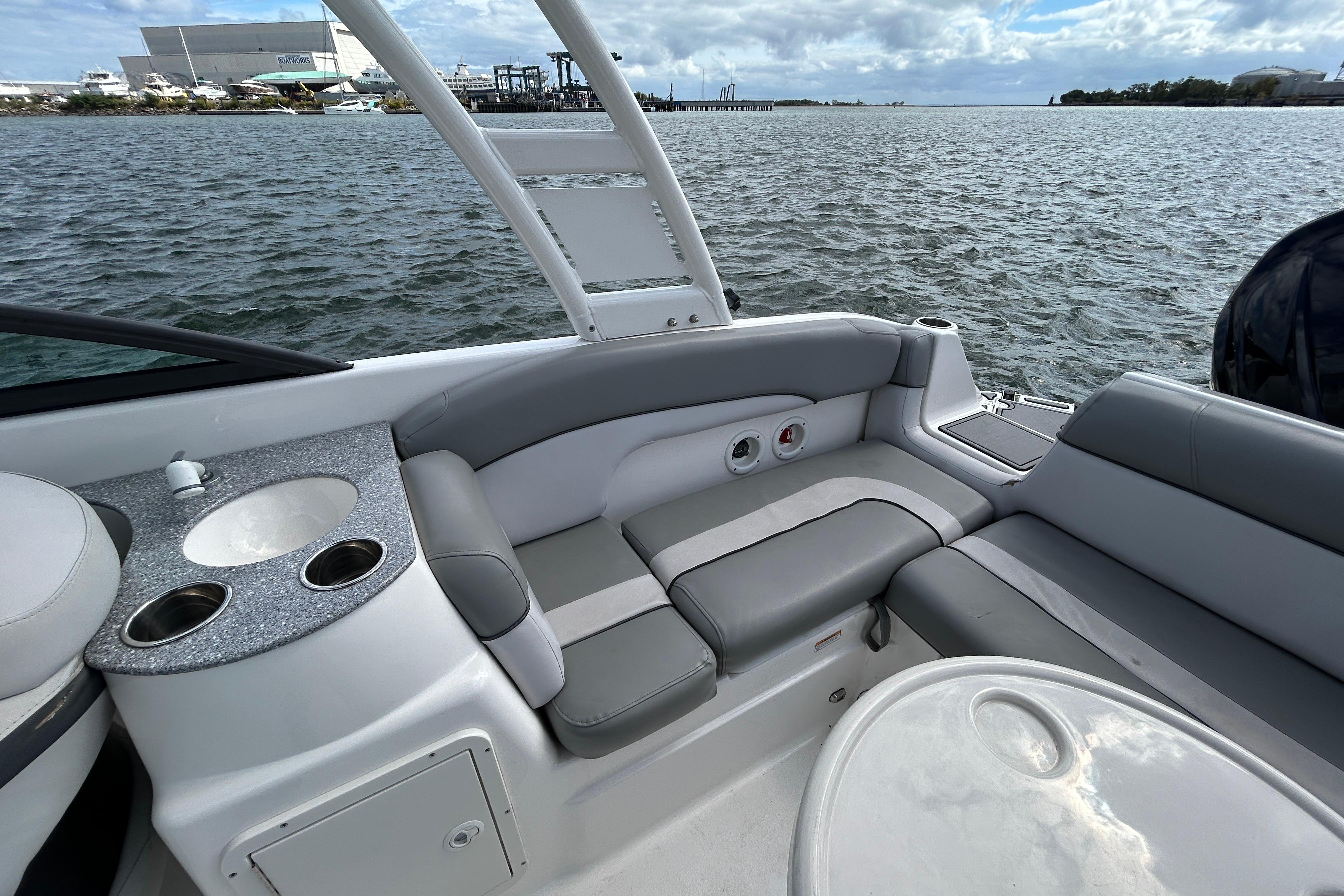 2022 NauticStar 243 DC boat interior with seating and cup holders on a calm water backdrop.
