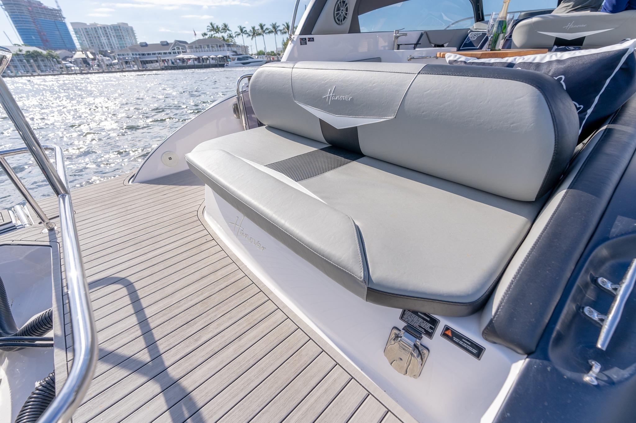 Luxurious seating on a 2027 Hanover 305 yacht, docked by a scenic waterfront.