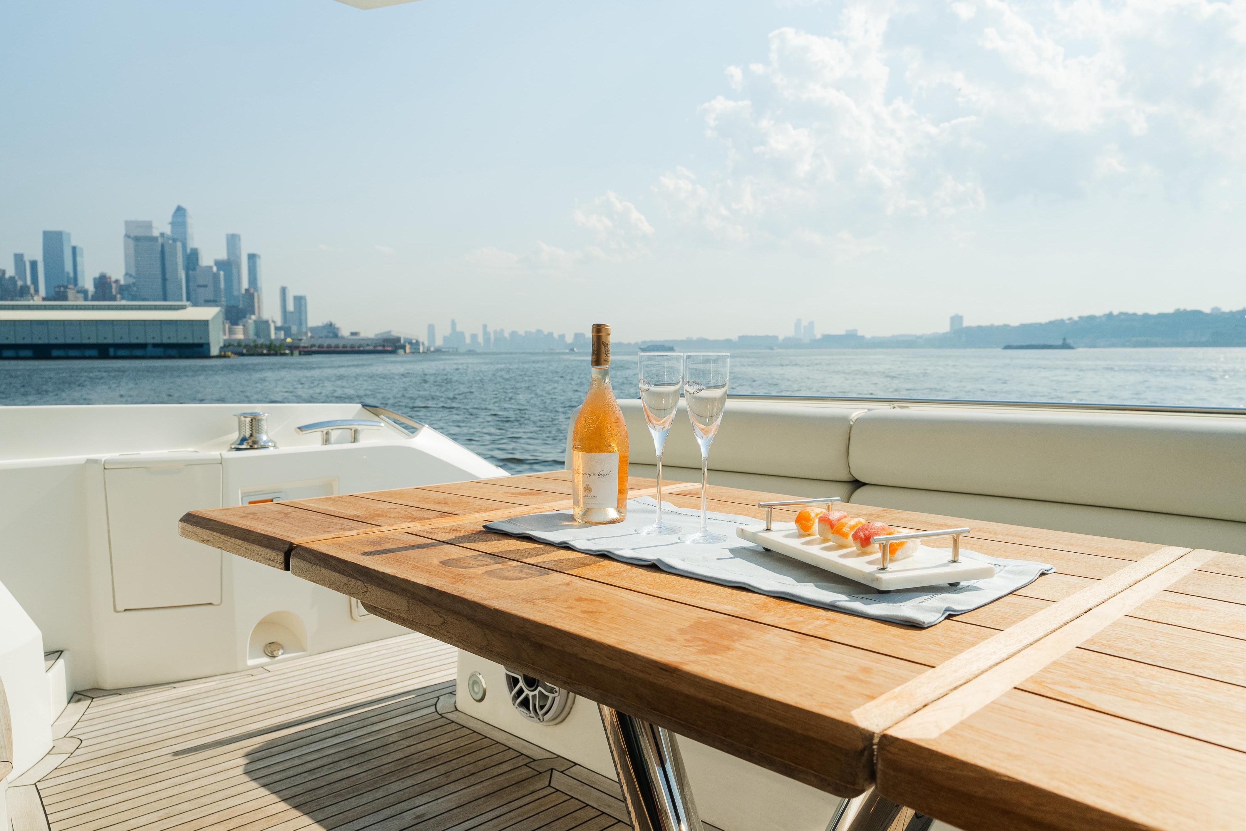 Luxurious Sunseeker Manhattan 65 yacht with city skyline, wine, and appetizers on deck.