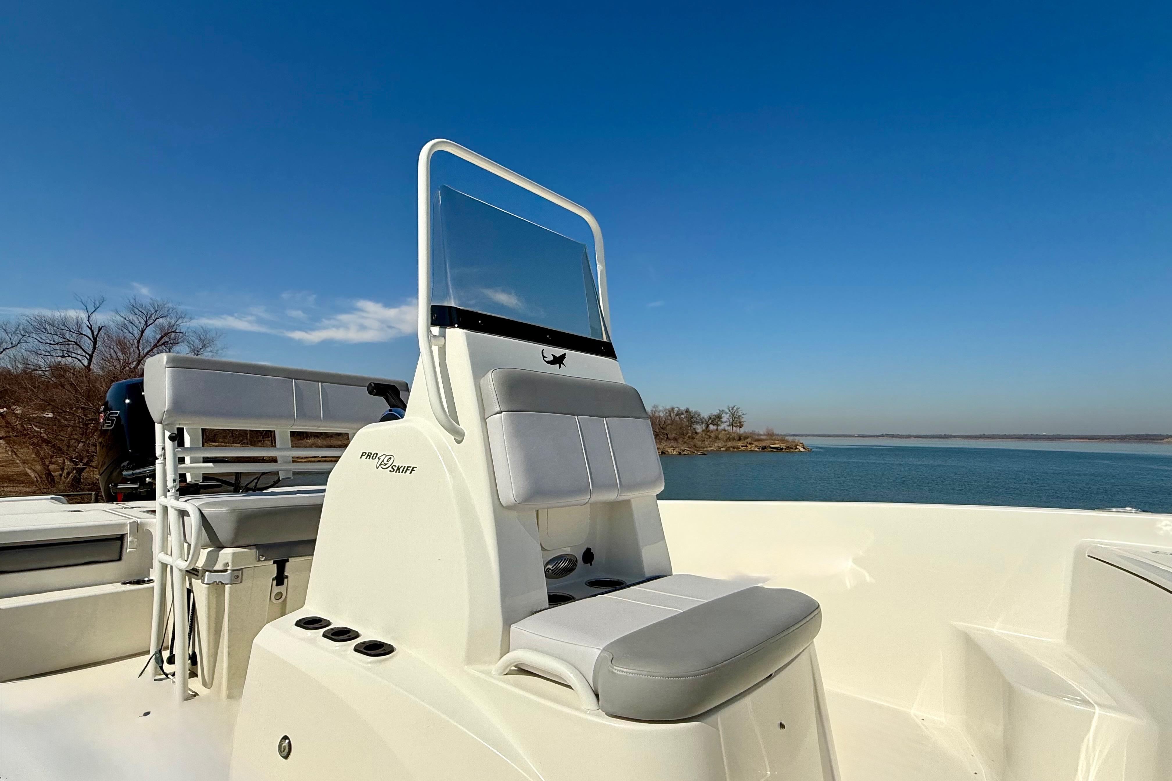 2024 Mako Pro Skiff 19 CC boat on calm water under clear blue sky.