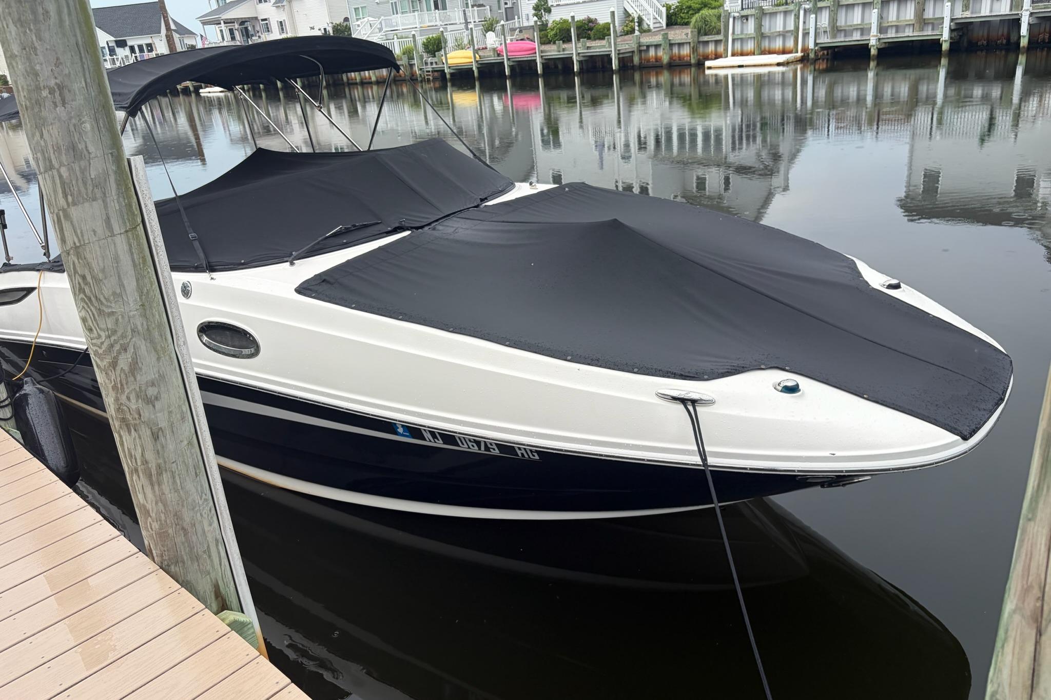 2014 Sea Ray 260 Sundeck boat docked with black covers in a serene marina.