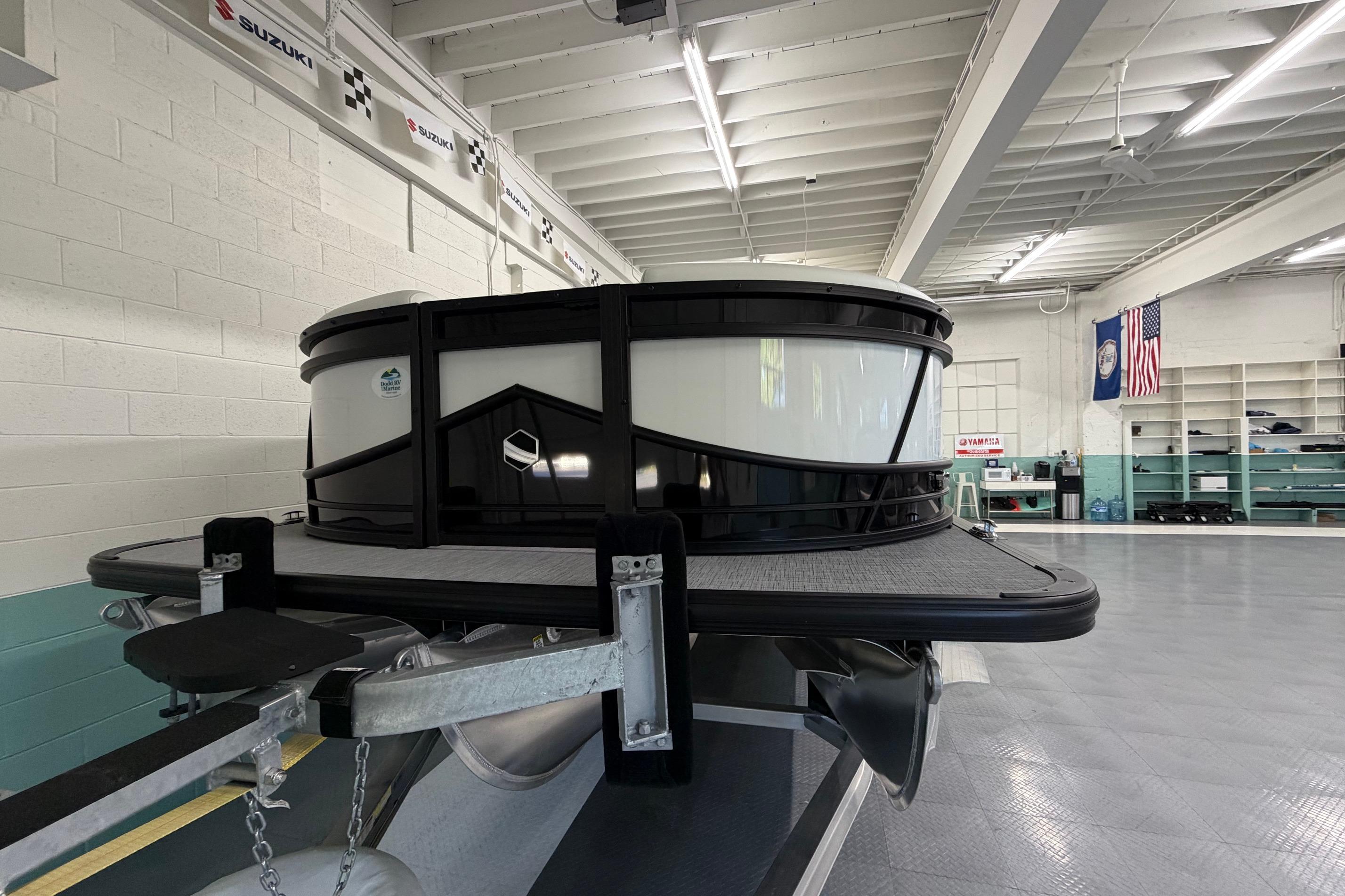 2026 South Bay 525SB2 pontoon boat in a showroom with flags and banners.