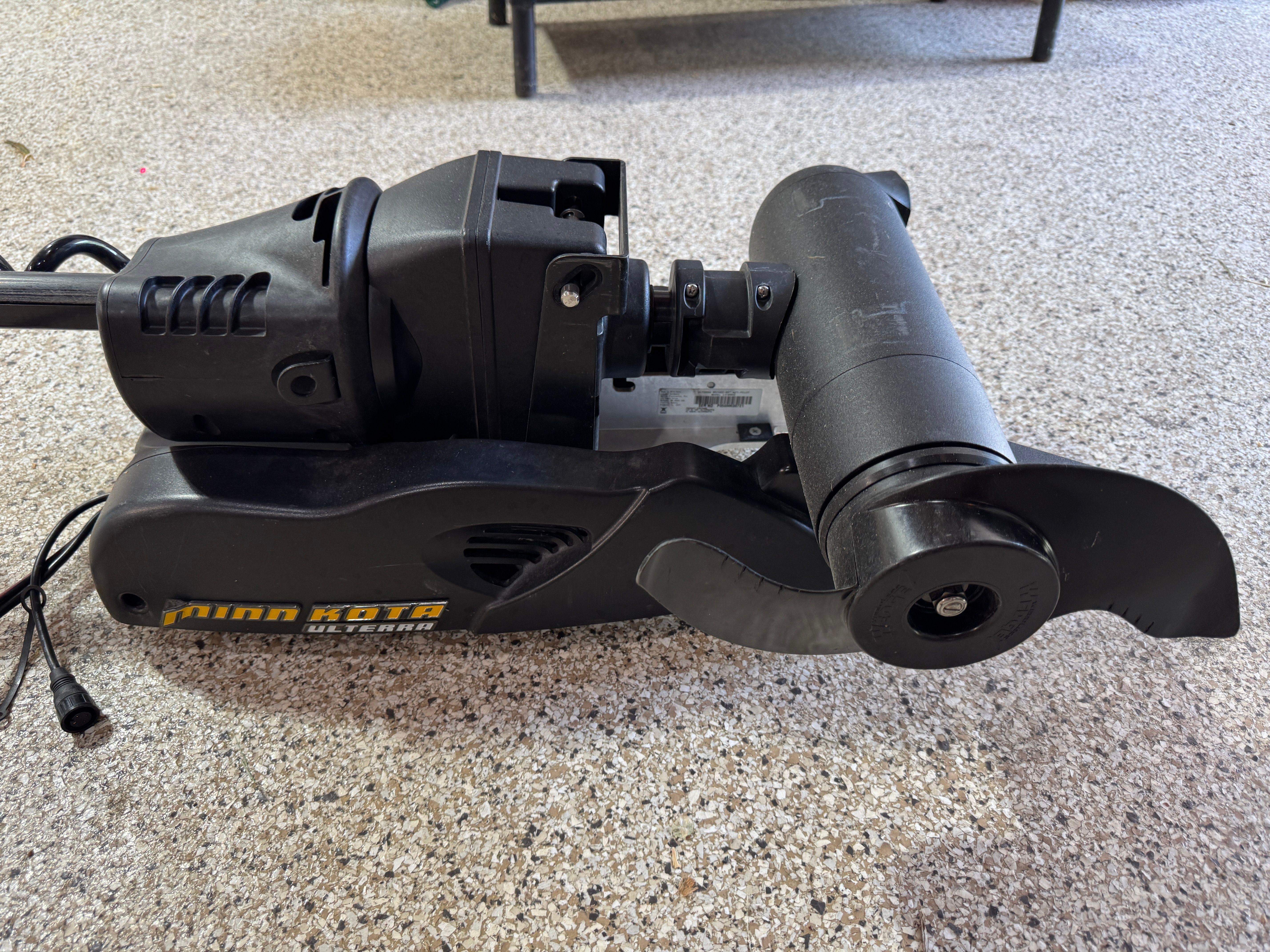 A Minn Kota Ulterra trolling motor on a carpeted floor.