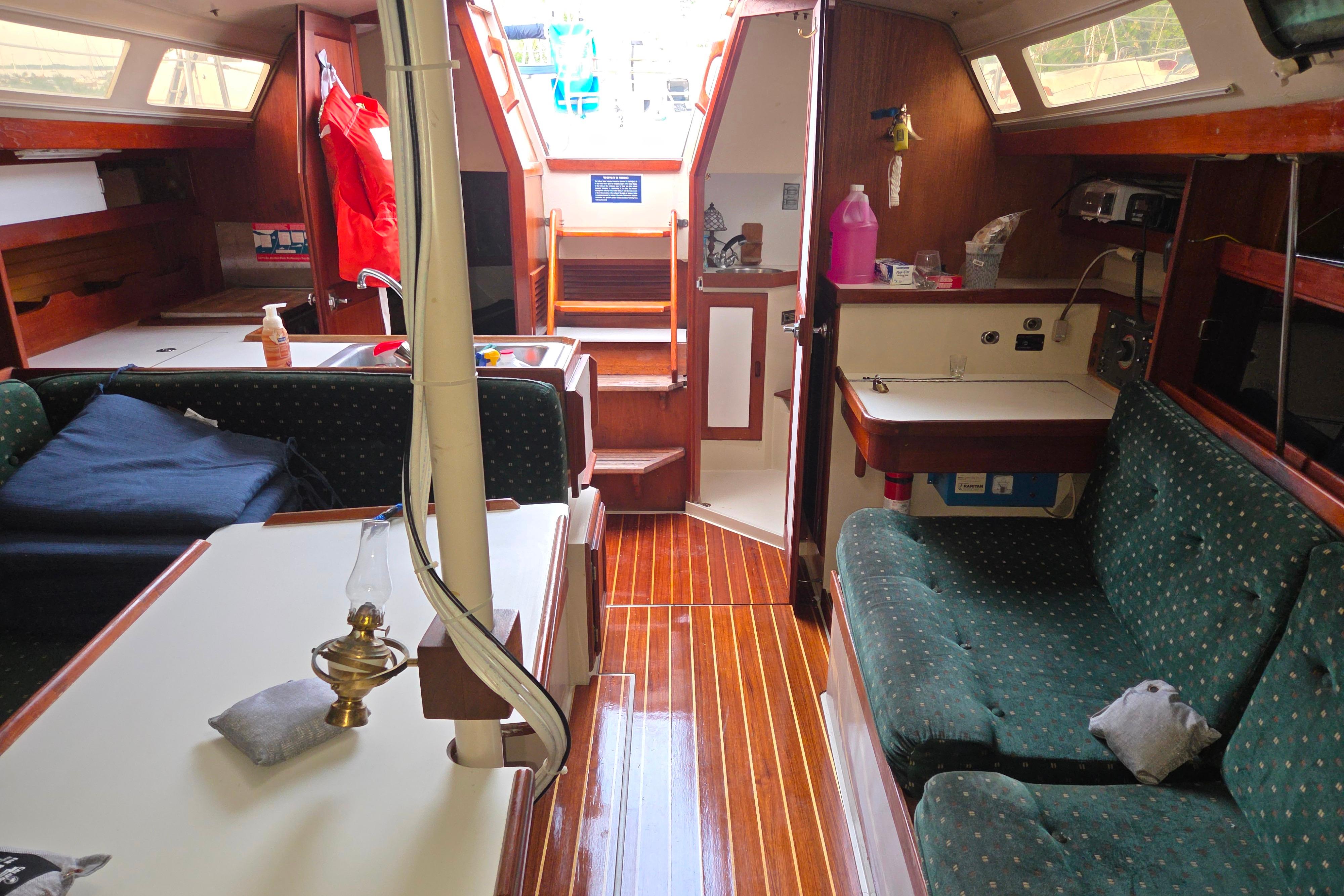 Interior of a 1986 Catalina 355 sailboat with wood finishes and green upholstery.