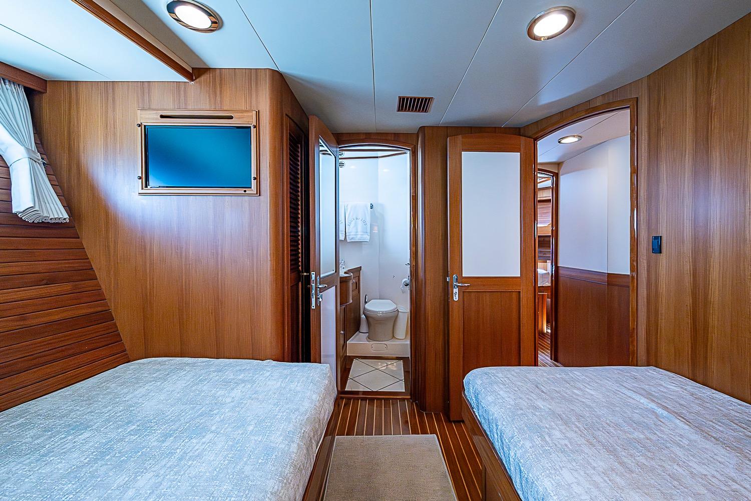 Luxurious cabin interior of 2014 Marlow 80 Explorer yacht with twin beds and ensuite bathroom.