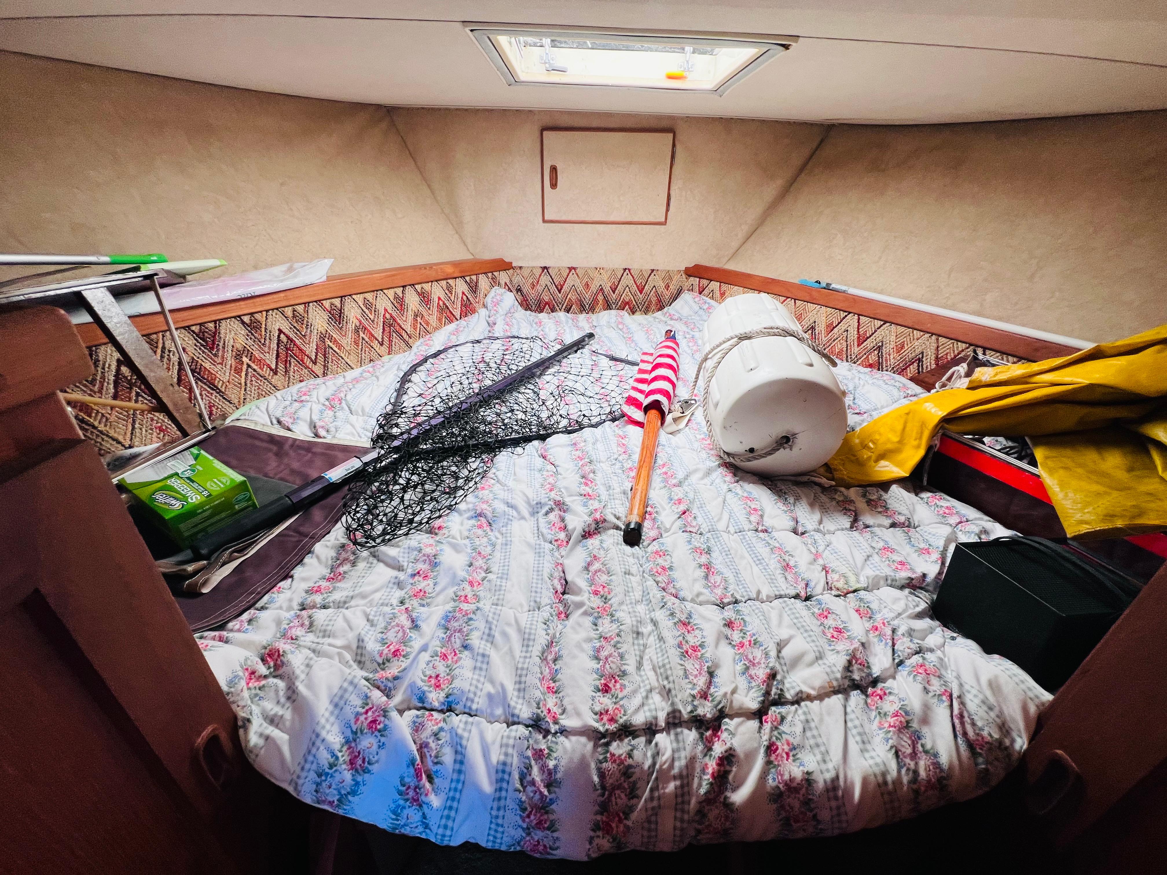 Cozy cabin interior of 1982 Trojan F32 boat with fishing gear and bedding.