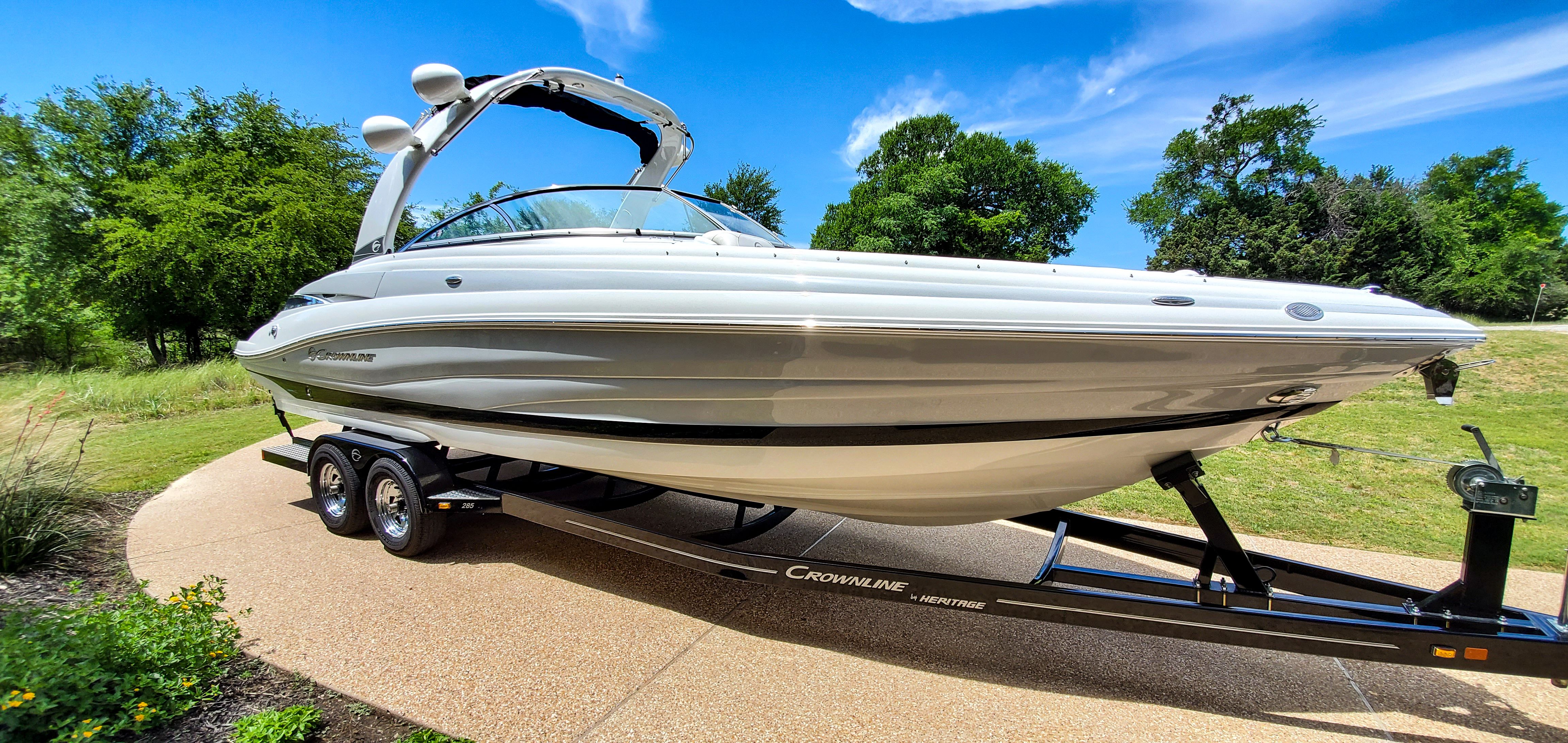 A 2017 Crownline 285SS boat on a trailer in a green setting.
