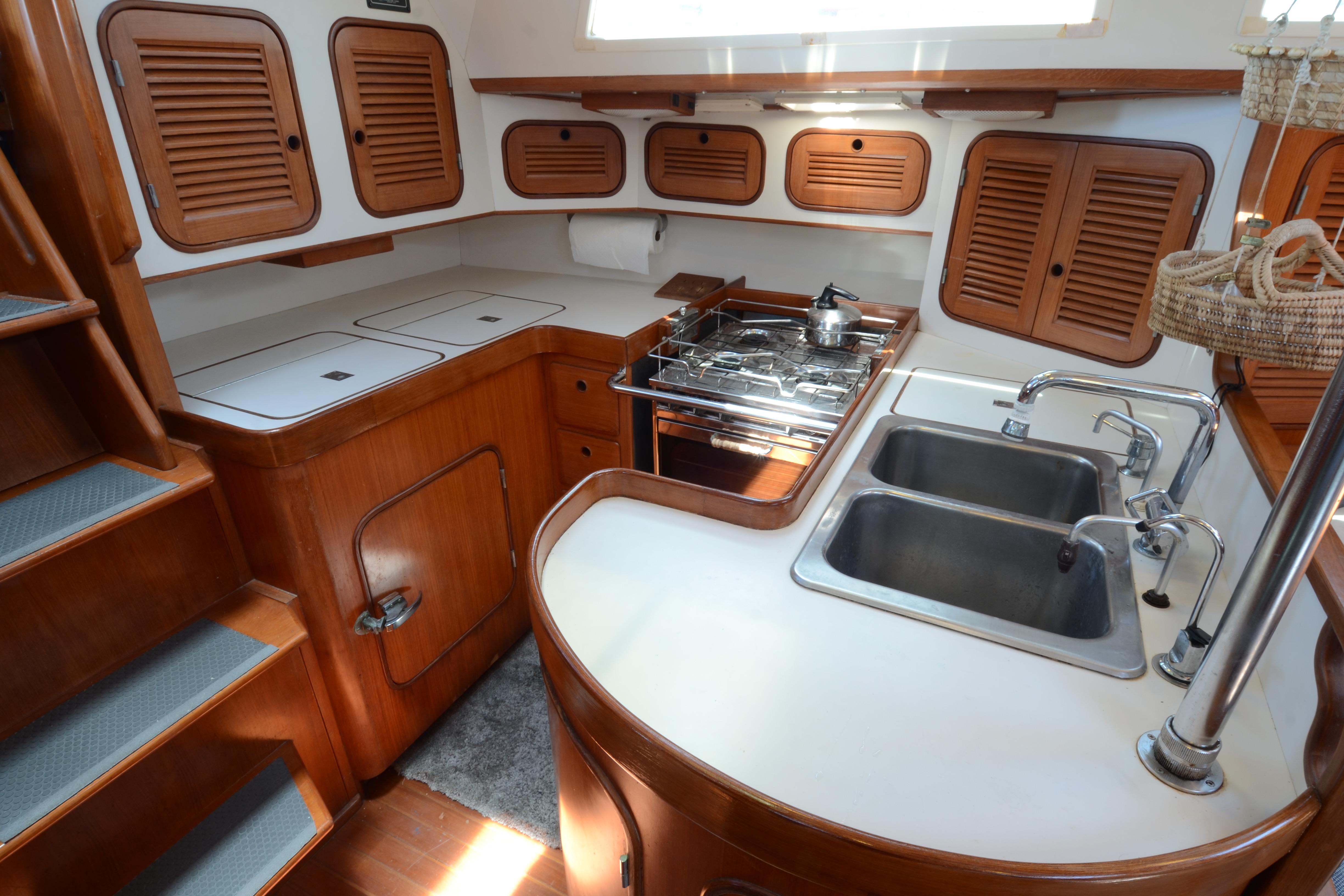 1987 Norseman 400 yacht kitchen with wooden cabinets, dual sinks, and stove.