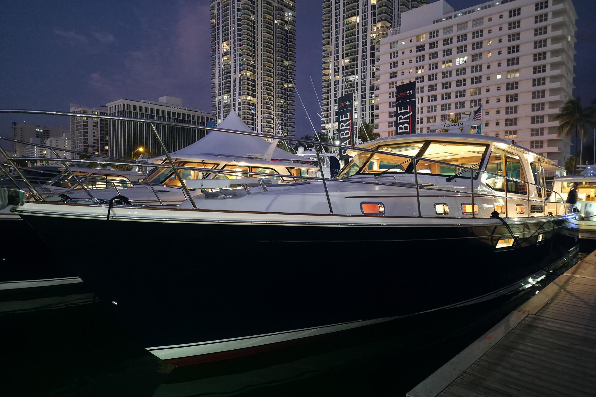 2026 Sabre 51 Salon Express yacht docked at night, illuminated against city skyline.