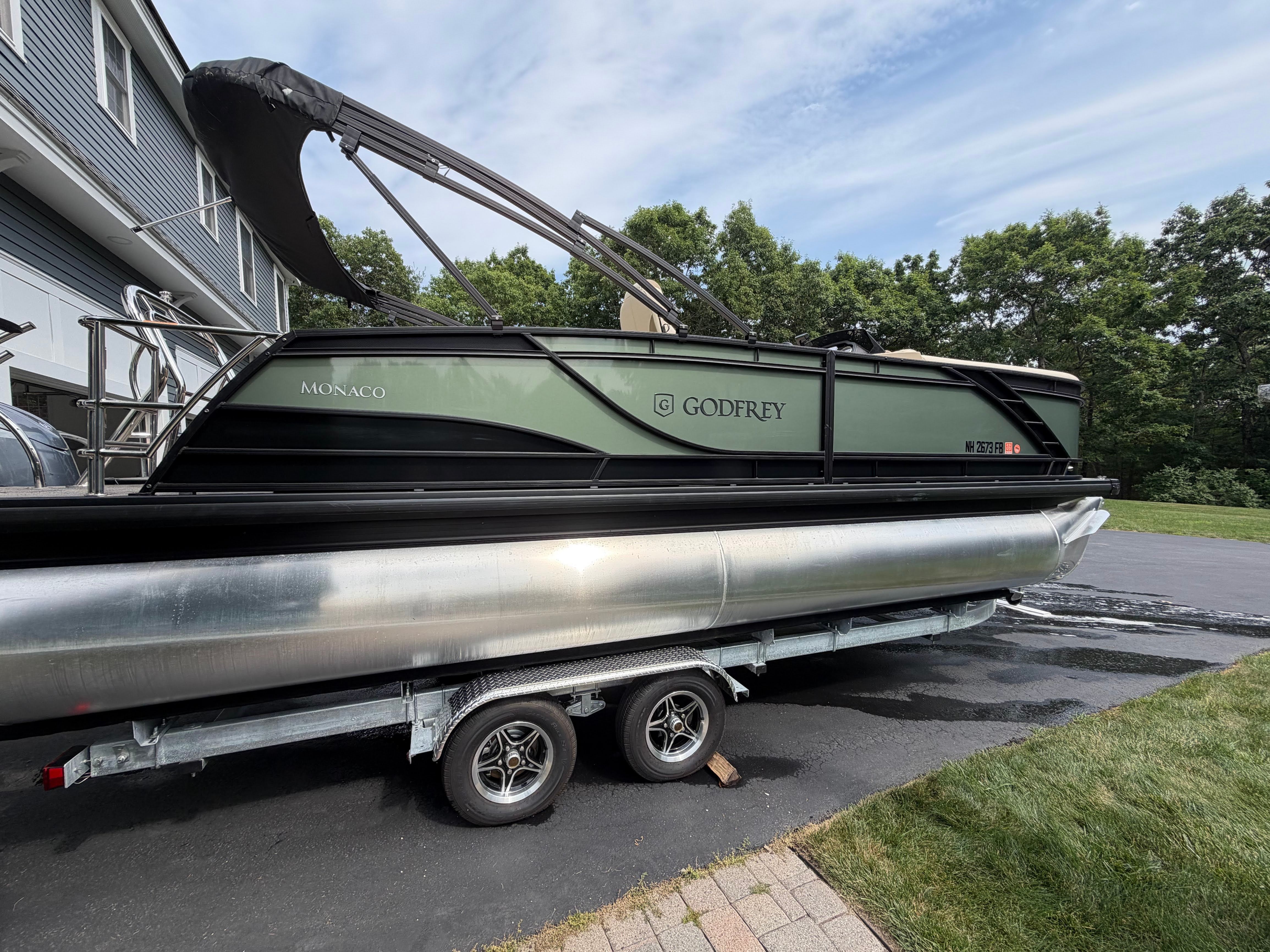 A 2025 Godfrey Monaco Cruise pontoon boat on a trailer, ready for use.