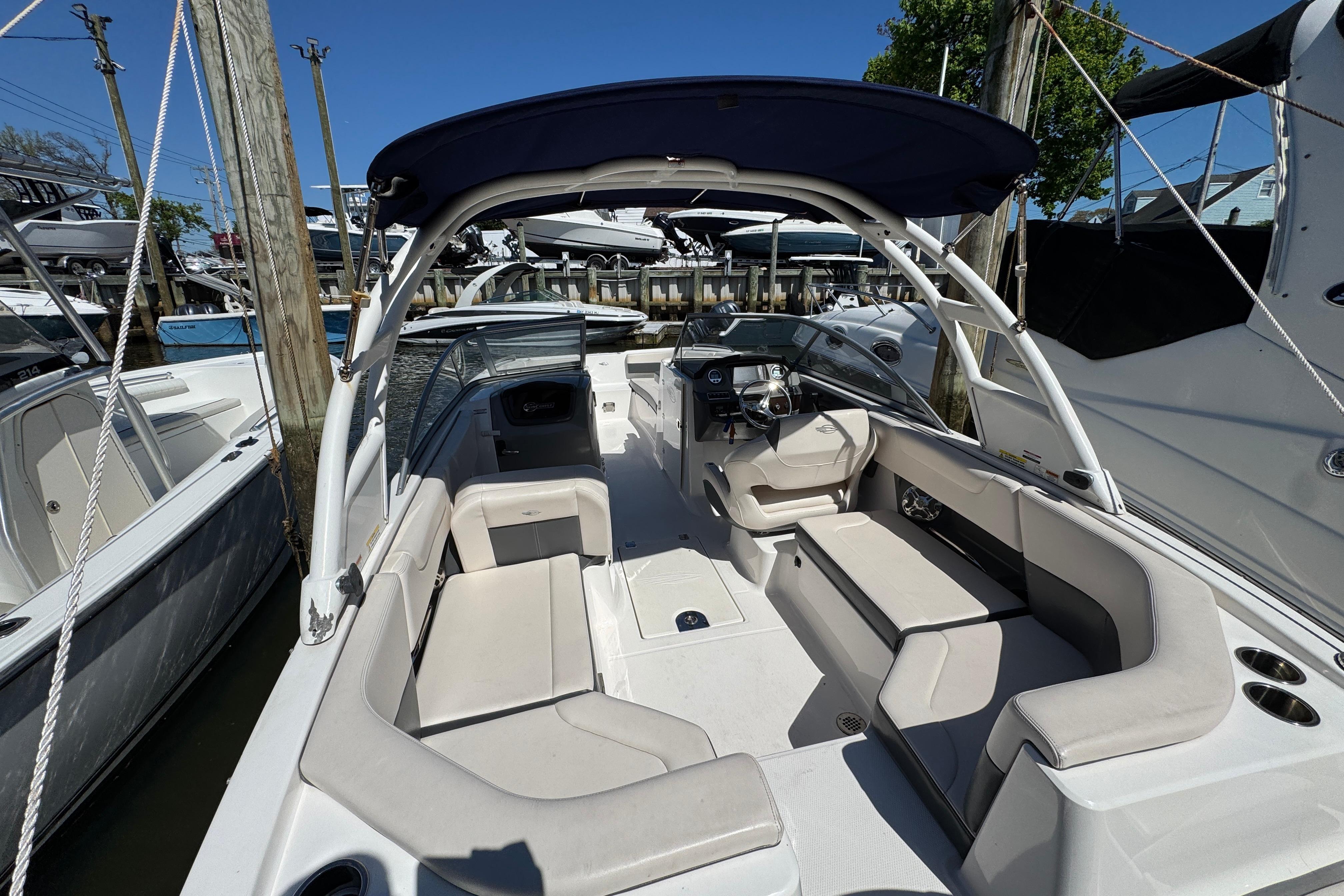 2018 Chaparral 250 Suncoast boat interior with seating and steering wheel, docked at marina.