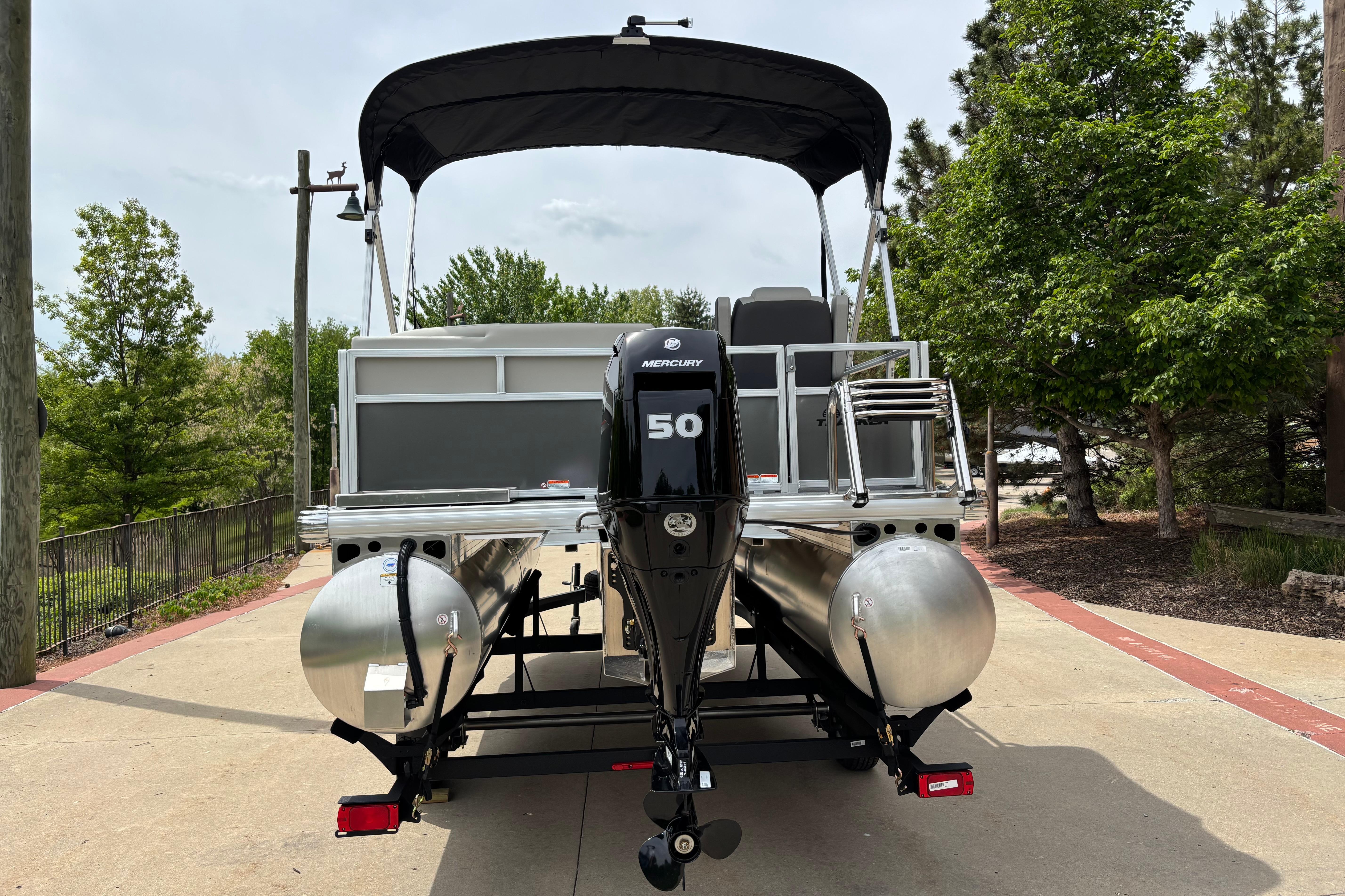 2026 Sun Tracker Bass Buggy 16 XL Select pontoon boat with Mercury 50 engine, parked outdoors.