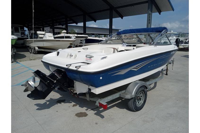2008 Bayliner 175 boat on trailer, blue and white, parked in marina.
