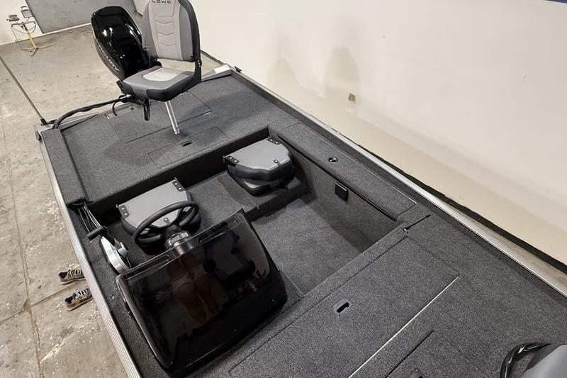 2026 Lowe Skorpion 16 boat interior with steering console and seating, in a garage setting.
