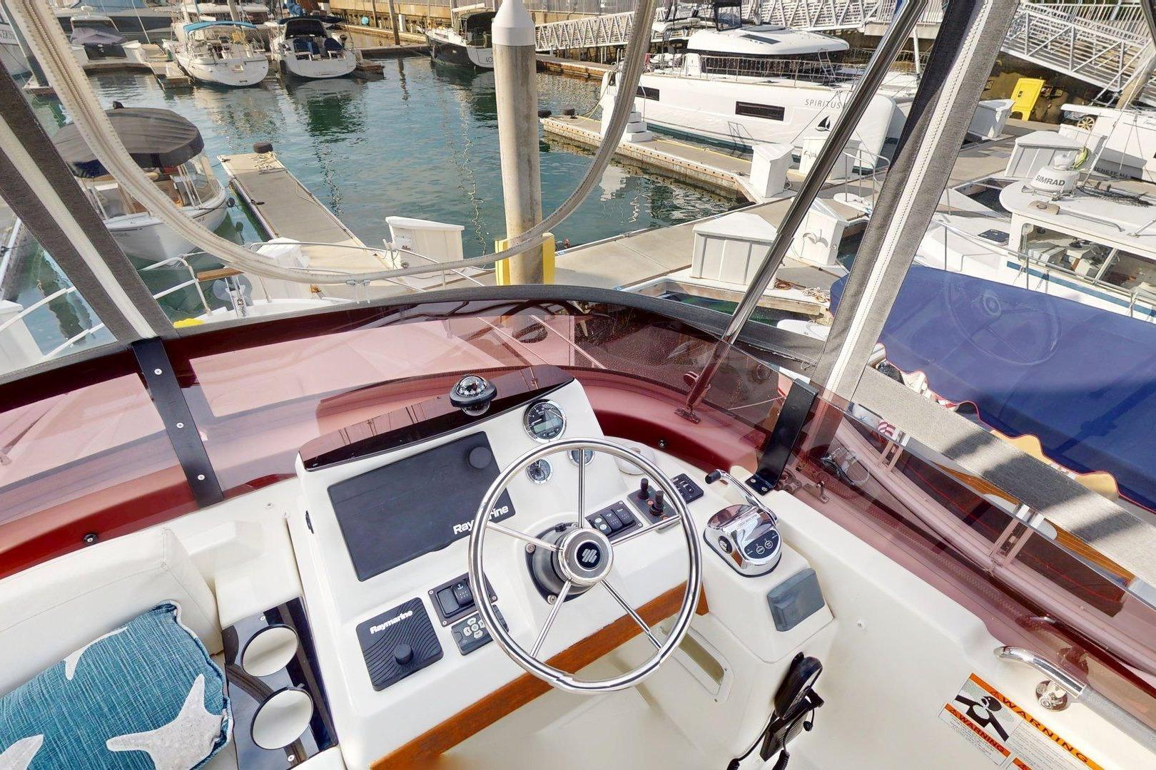 Cockpit view of 2021 Beneteau Swift Trawler 35 at marina, showcasing helm and controls.