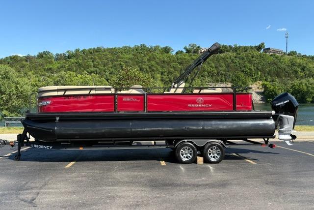 2025 Regency 250 DL3 pontoon boat on trailer, parked outdoors with scenic background.