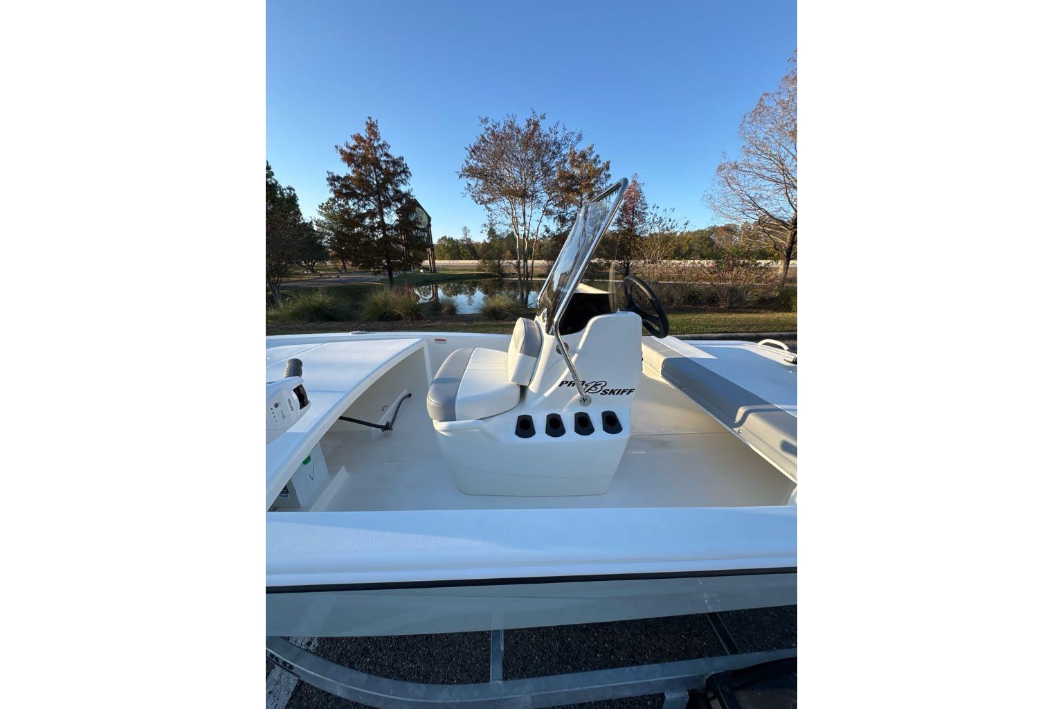 2026 Mako Pro Skiff 13 CC boat with console and seating, set against a scenic outdoor backdrop.