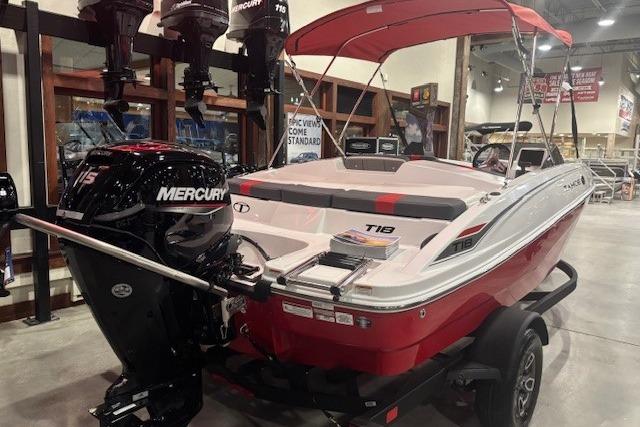 2026 Tahoe T18 boat with Mercury engine, red and white design, displayed indoors.
