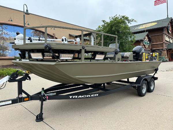 2025 Tracker Grizzly 2072 CC Sportsman boat on trailer, outdoors, near a building.