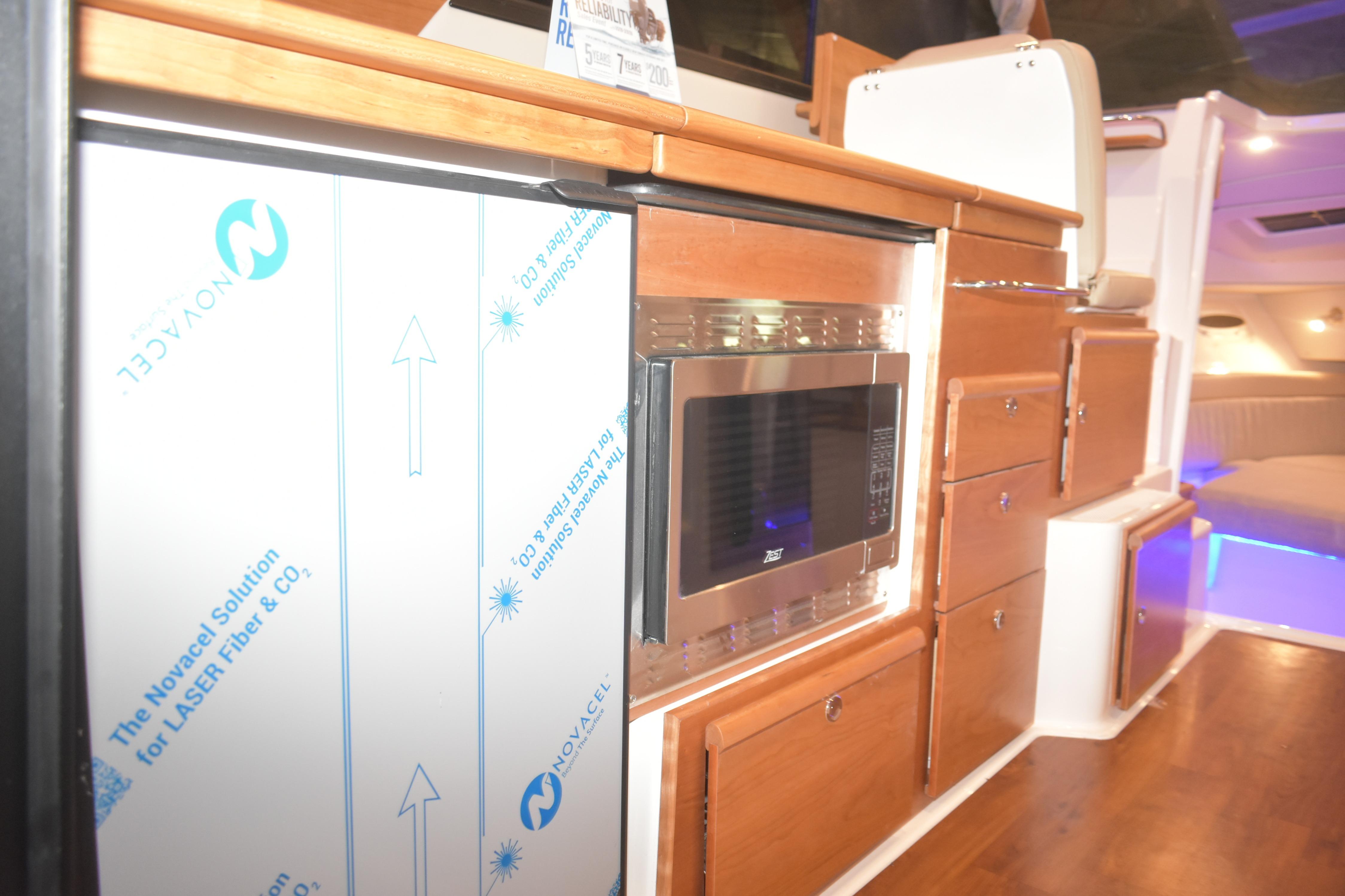 Interior of 2026 Cutwater C-32 CB boat featuring modern kitchen appliances and wooden cabinetry.