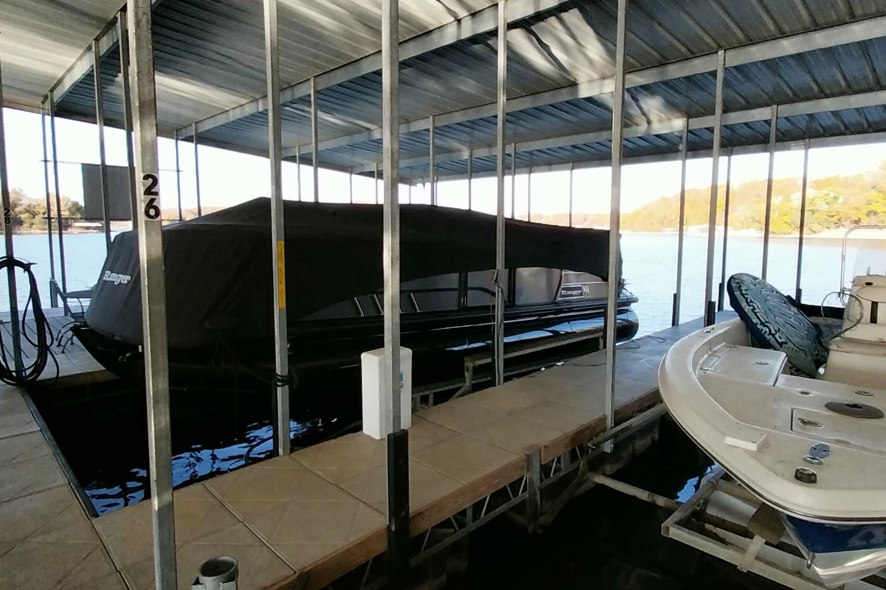 Covered 2023 Ranger 2500LS boat docked in a marina with scenic lake view.