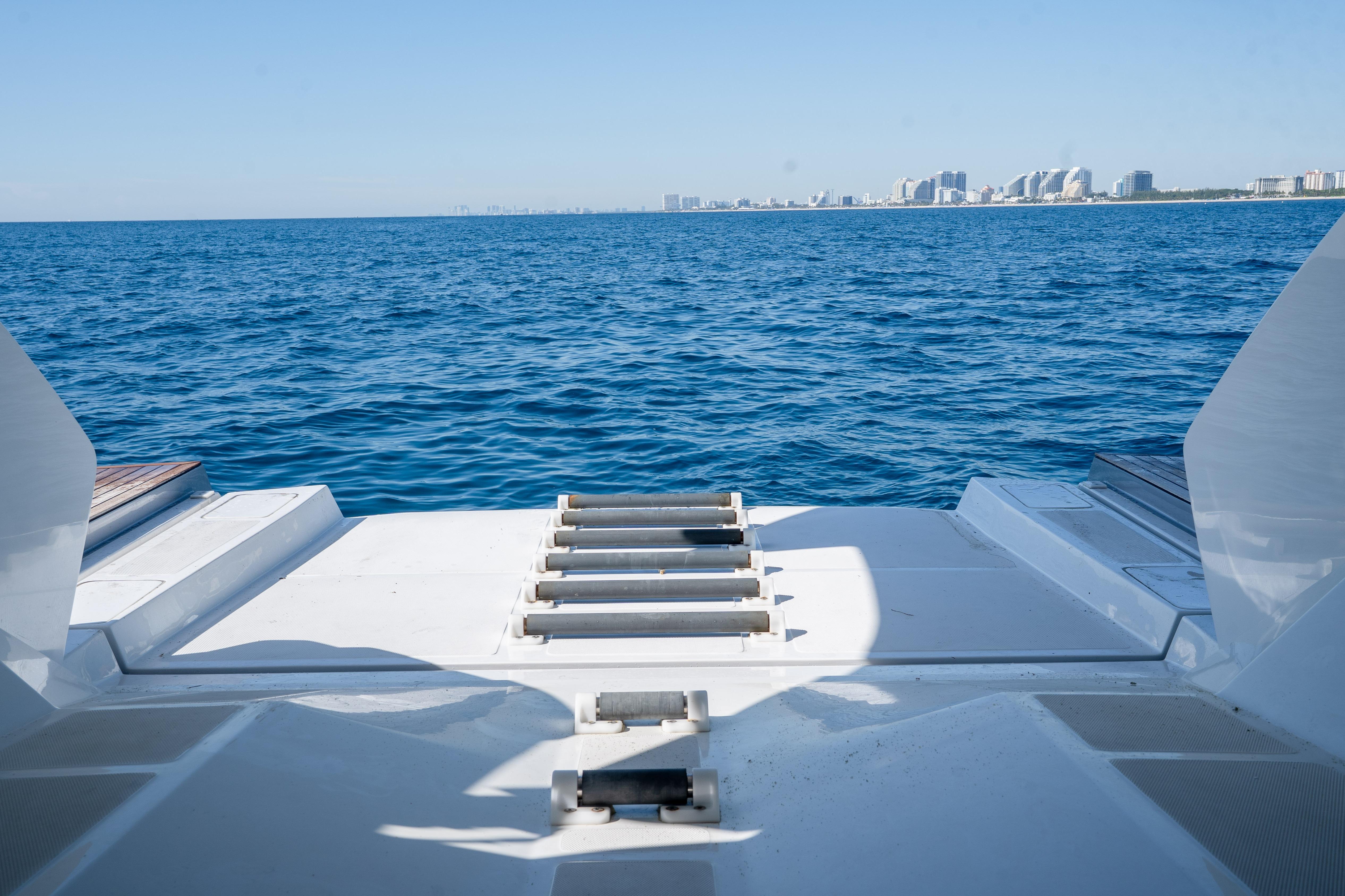 2024 Pershing 7X yacht deck overlooking ocean and distant city skyline.