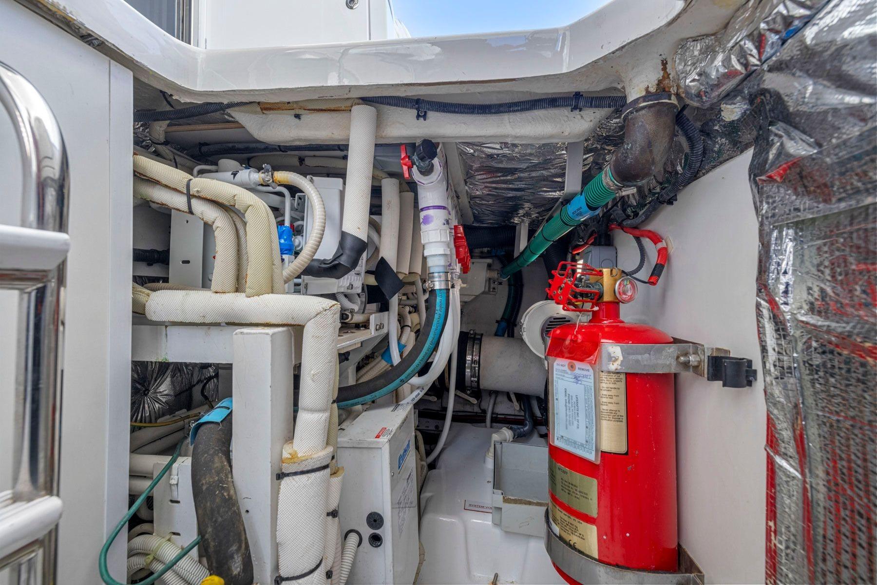 Engine room of a 2015 Princess 60 Flybridge Motor Yacht with fire extinguisher and piping.