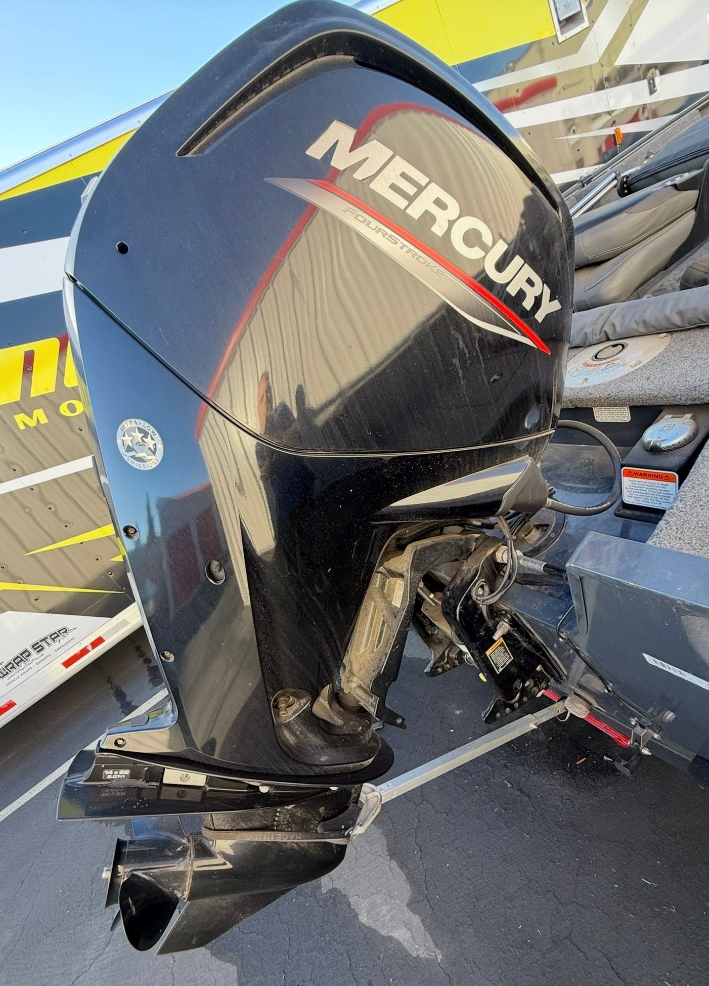 A Mercury outboard motor is attached to a boat on a trailer.