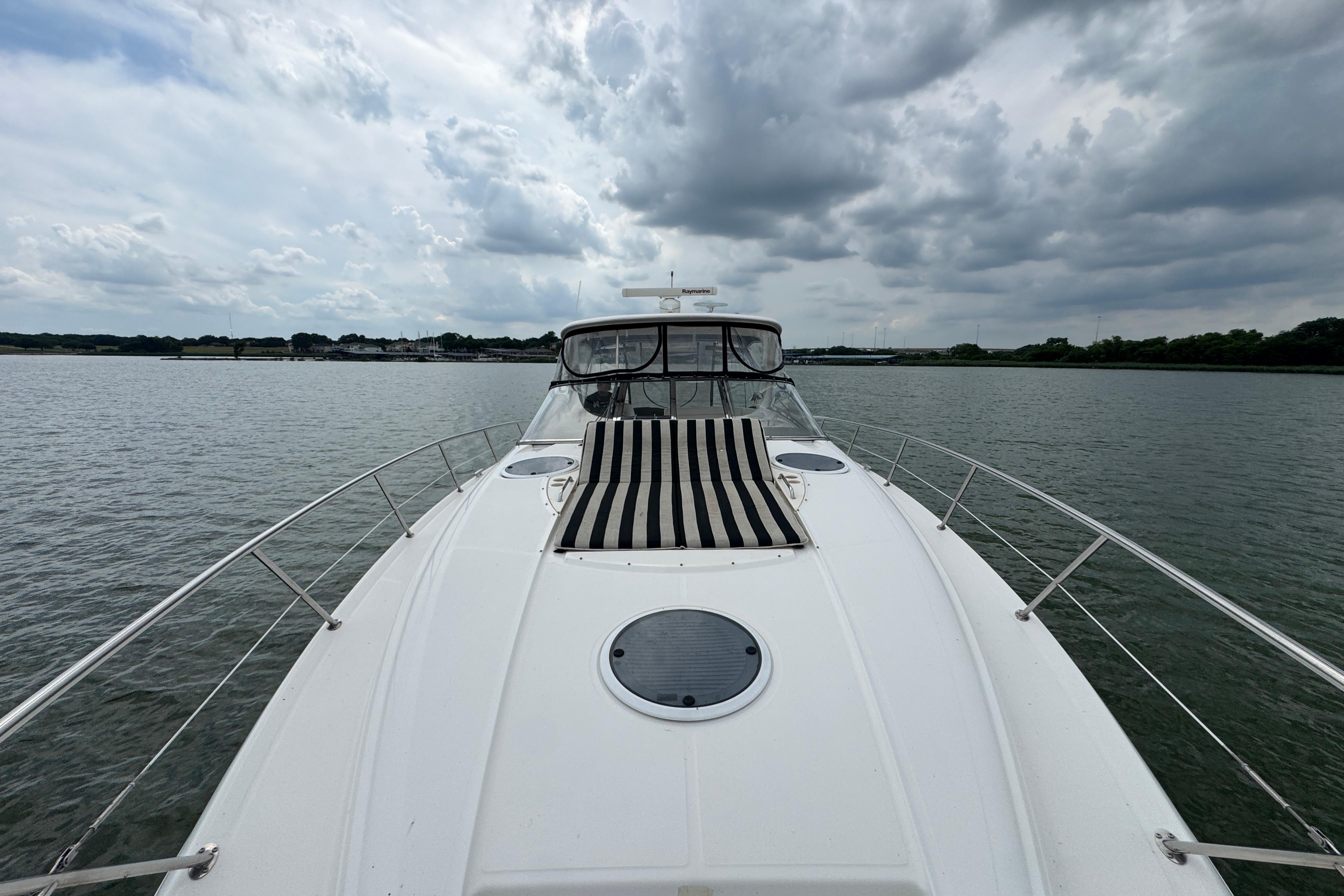 2005 Regal Commodore 4260 yacht on calm water under cloudy sky.