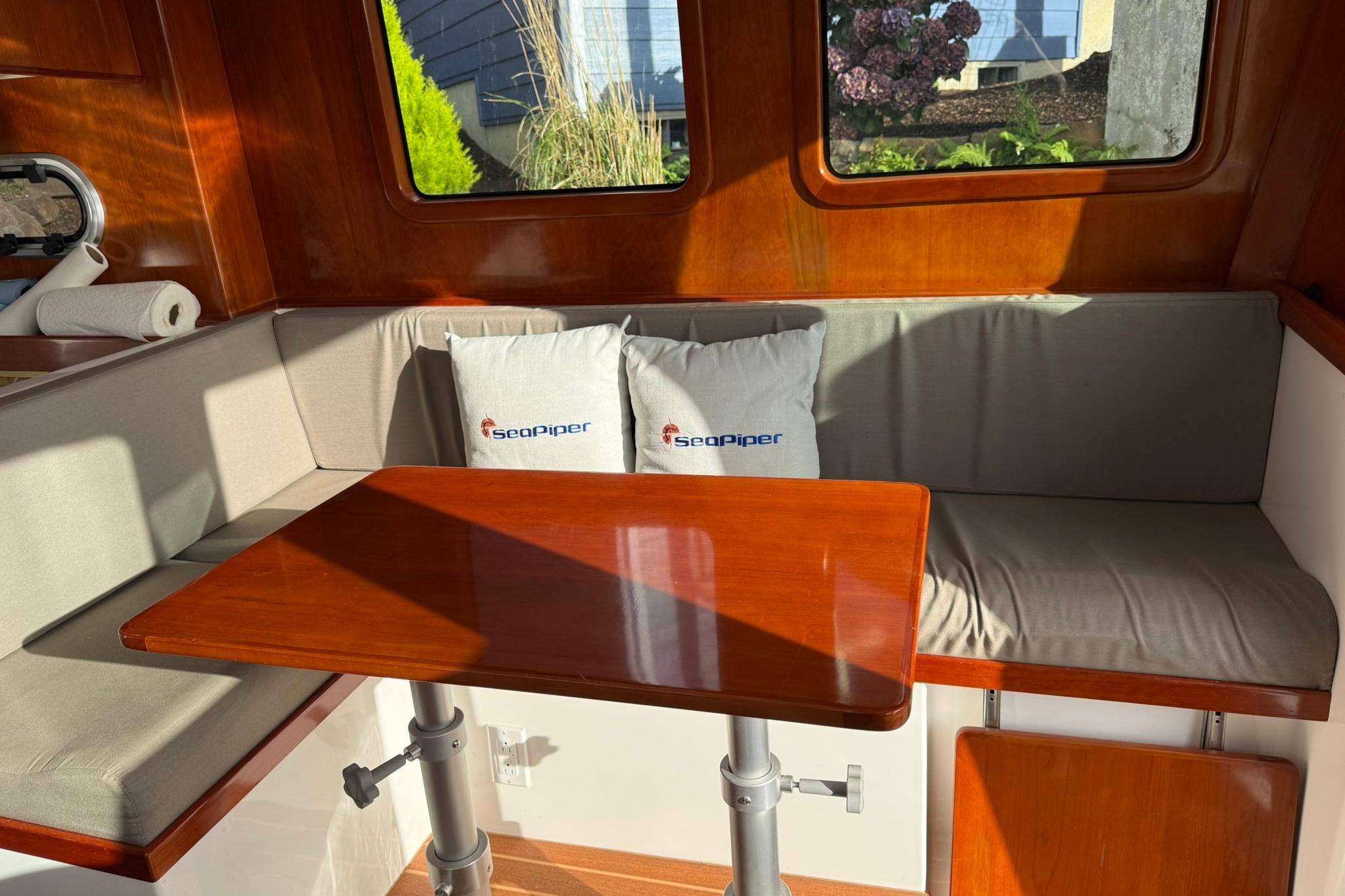 Cozy interior of 2020 SeaPiper 35 with wooden table and branded cushions.