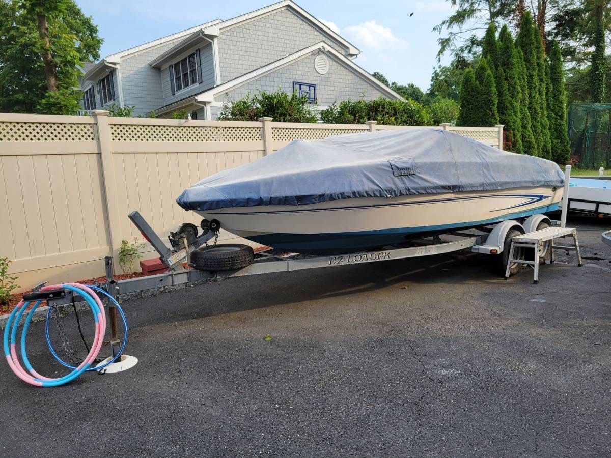 A 2006 Glastron MX-195 Limited Edition boat on a trailer, covered, in a driveway.