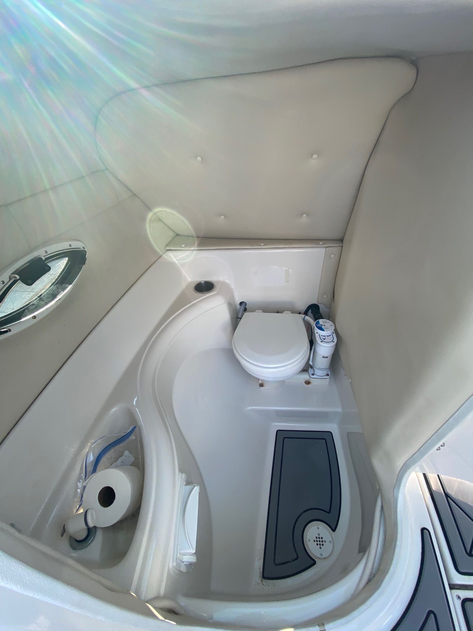The image shows a compact boat toilet with a porthole and a small sink.