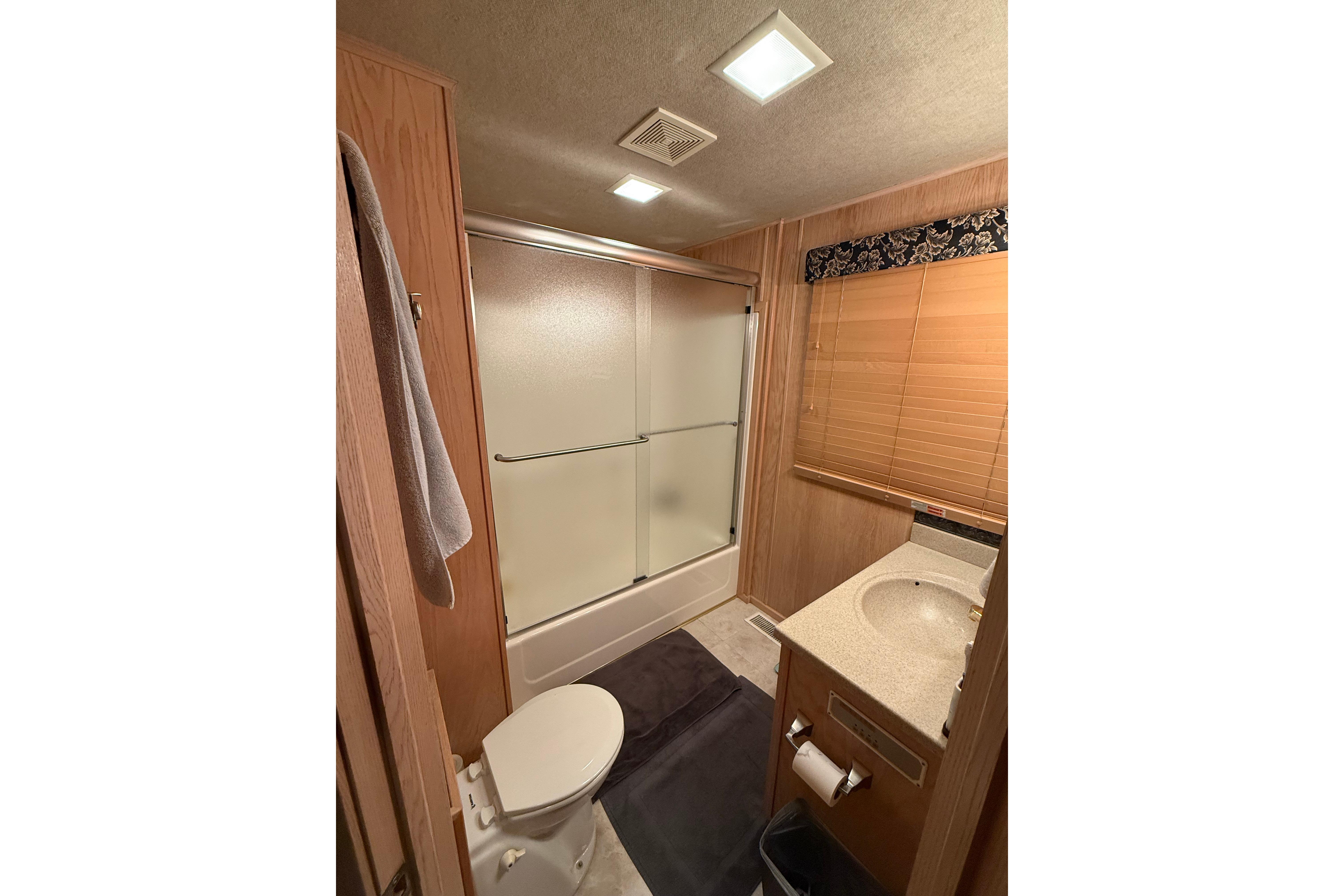 Bathroom interior of a 1998 Sumerset 16x76 houseboat with shower, toilet, and sink.