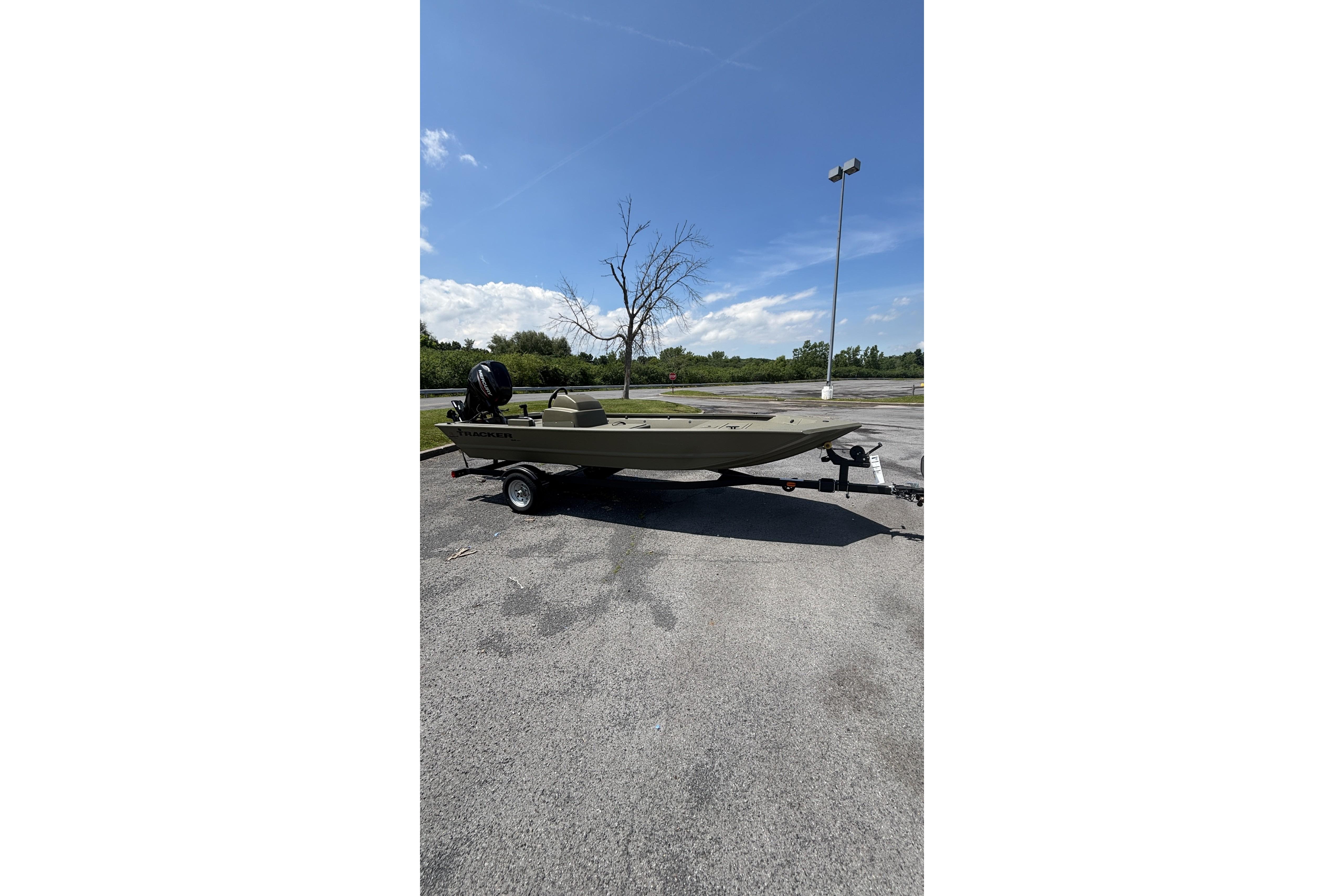 2026 Tracker Grizzly 1648 SC boat on trailer in parking lot under clear sky.