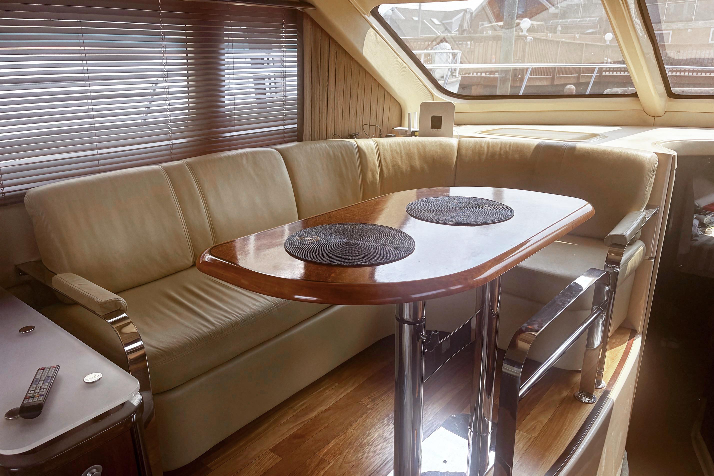 Luxurious interior of 2006 Sea Ray 52 Sedan Bridge yacht with leather seating and wooden table.