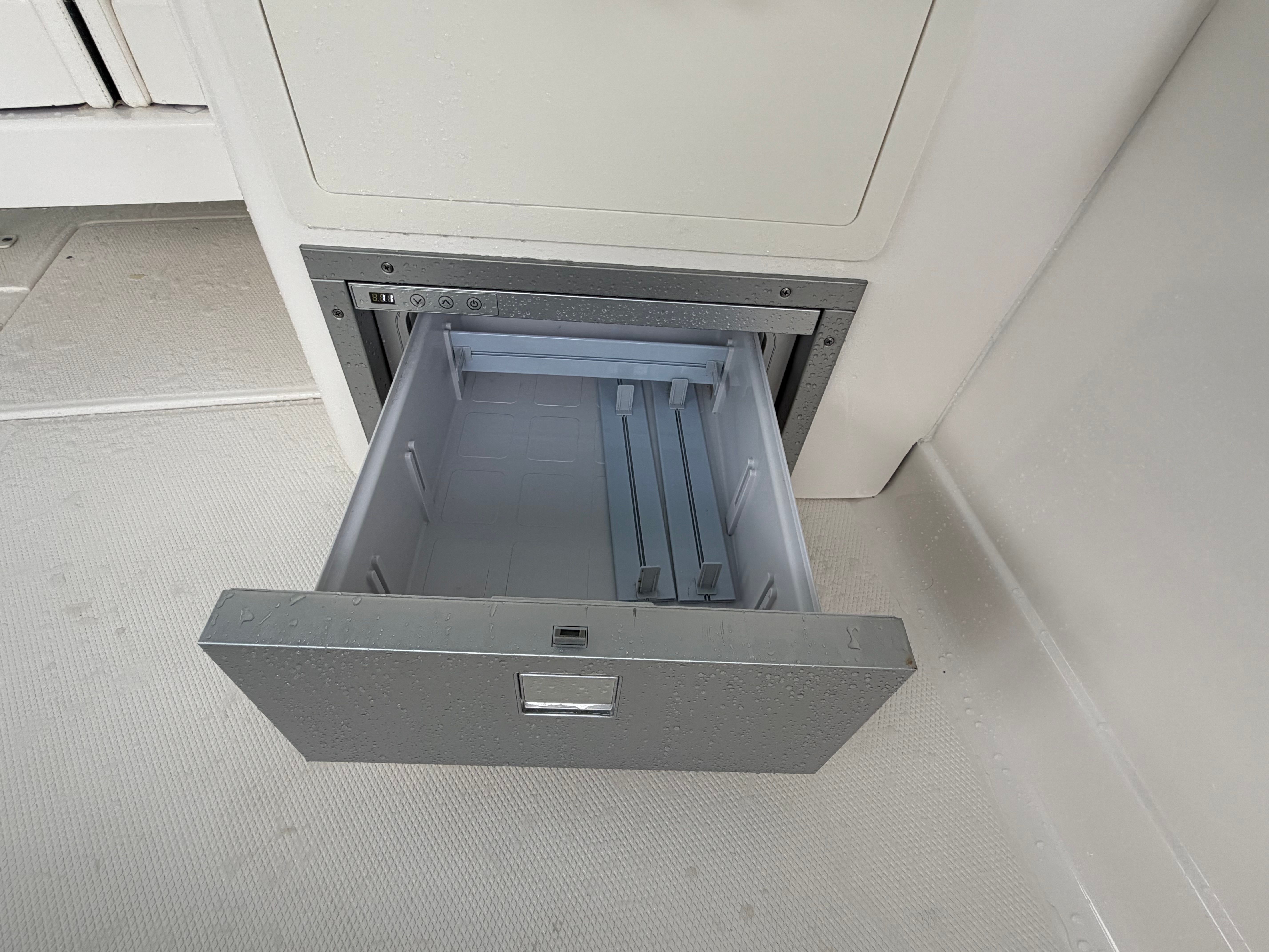 An open drawer on a boat, built into a white wall.