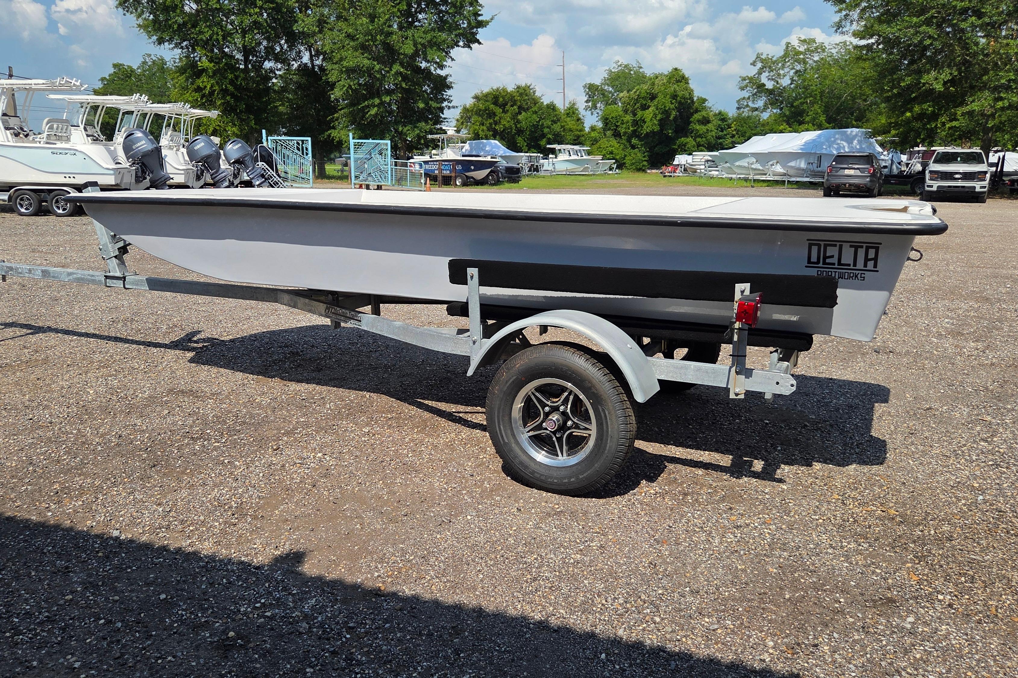 2027 Delta Boatworks 1550 on trailer, parked outdoors with trees and boats in the background.