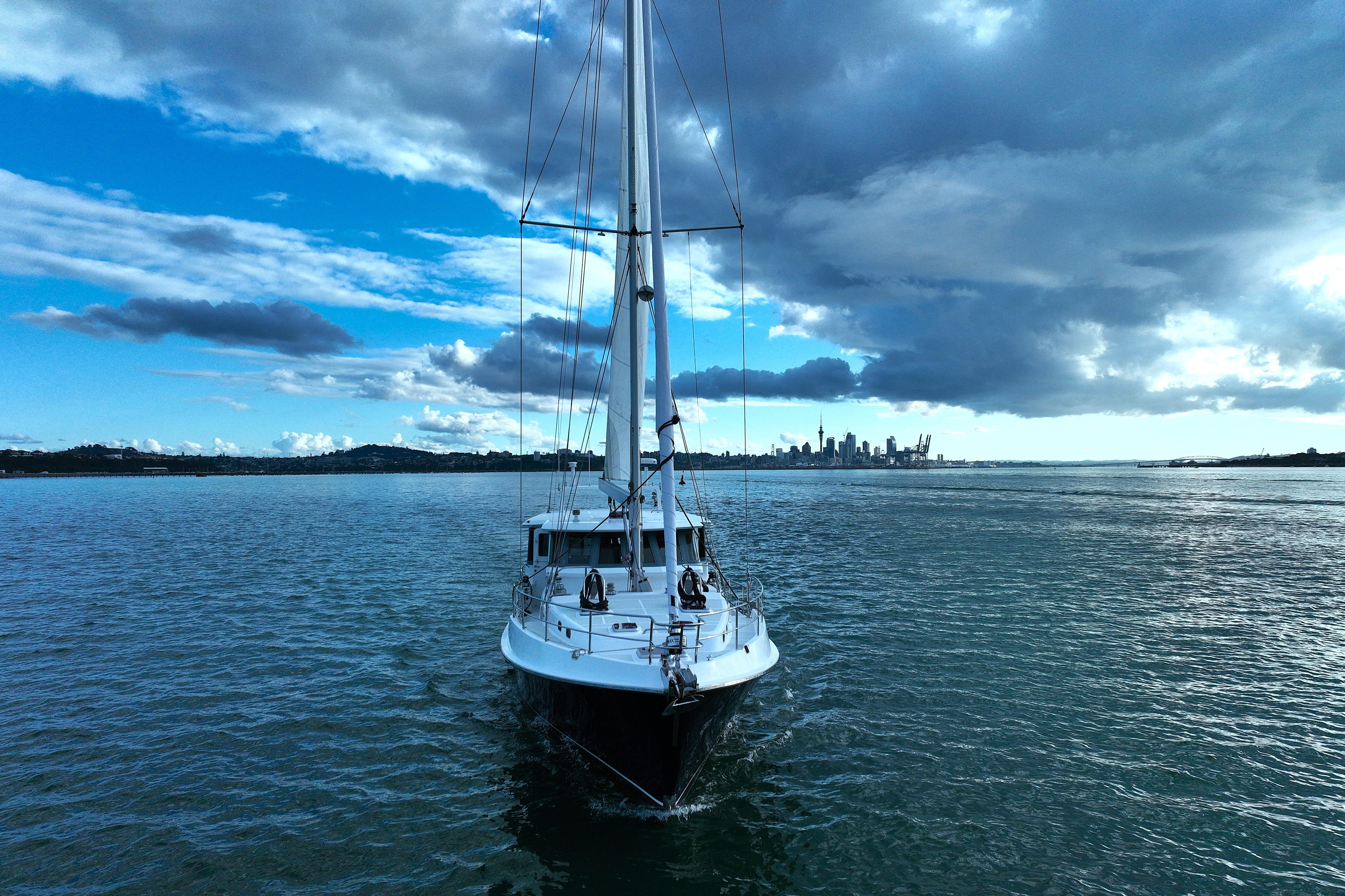 Nordhavn 56 Motorsailer 2009 sailing towards city skyline under dramatic clouds.