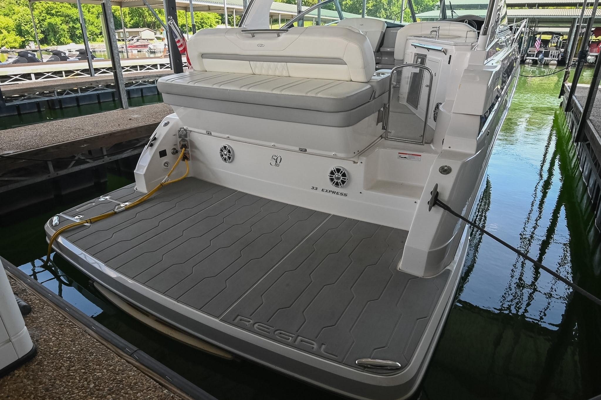 2021 Regal 33 Express boat docked, featuring spacious deck and seating area.