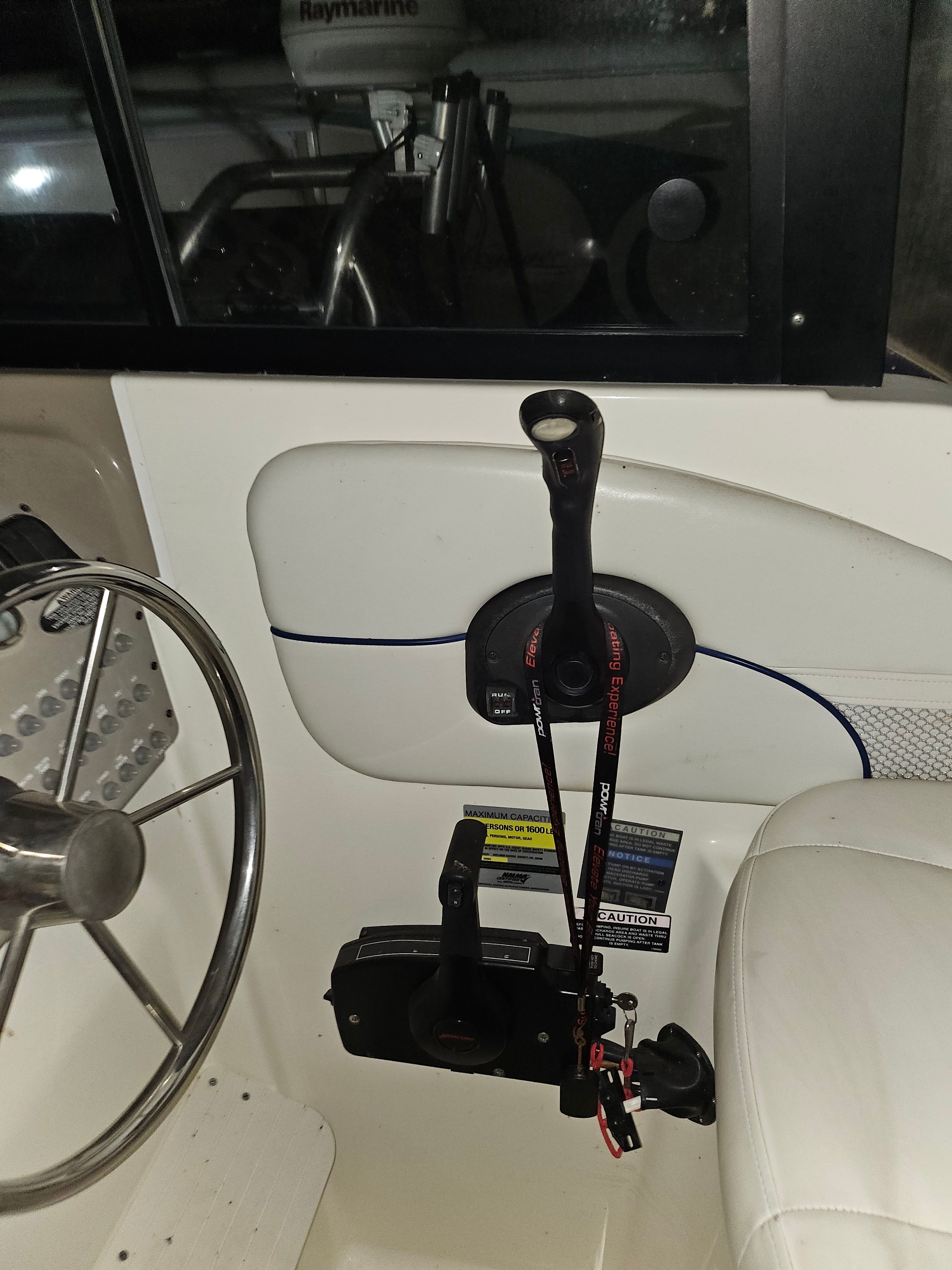 Close-up of the helm of a 2005 Bayliner 242 Ceara with steering wheel and levers.