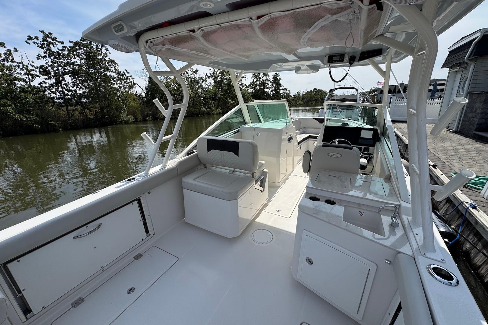 2022 Sailfish 276 DC boat interior with seating and helm, docked by a calm river.