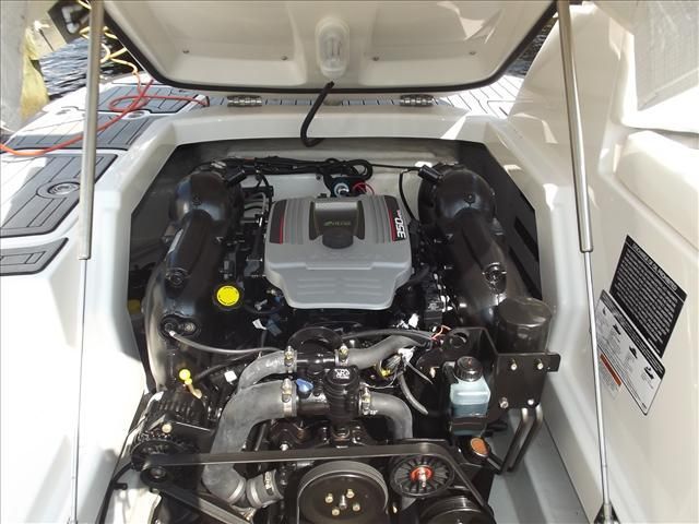 A boat engine in an open compartment, surrounded by white surfaces.