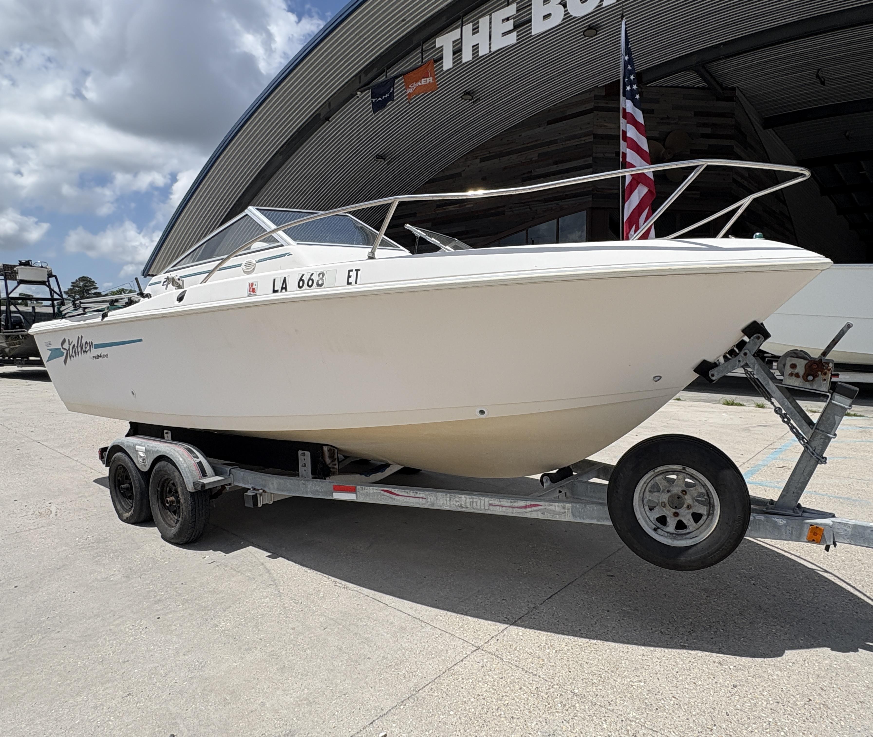 1996 Pro-Line 202 boat on trailer, parked outside a building with an American flag.