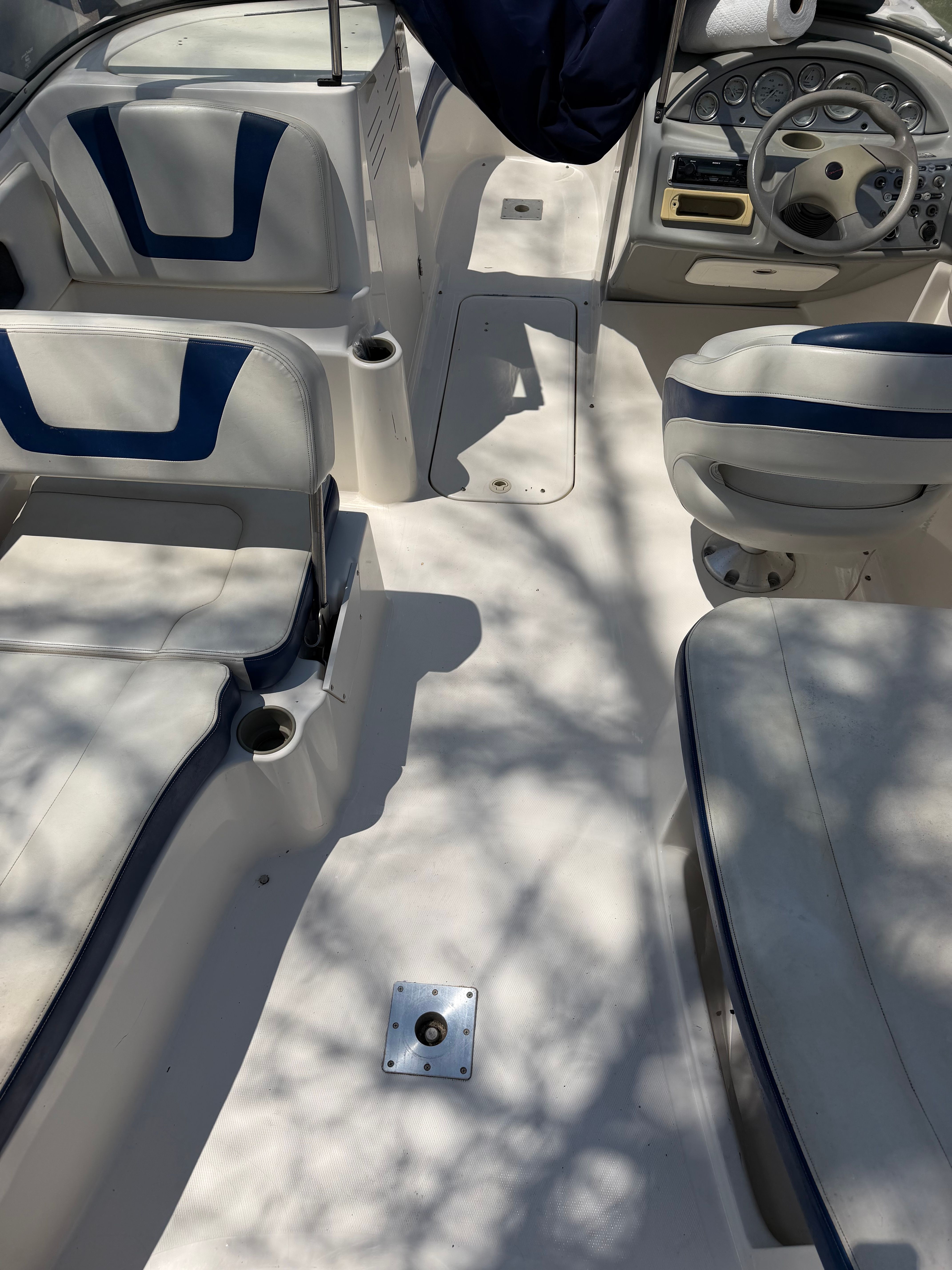 The image shows the cockpit of a 2005 Bayliner 212 Open Bow boat with white and blue seating.